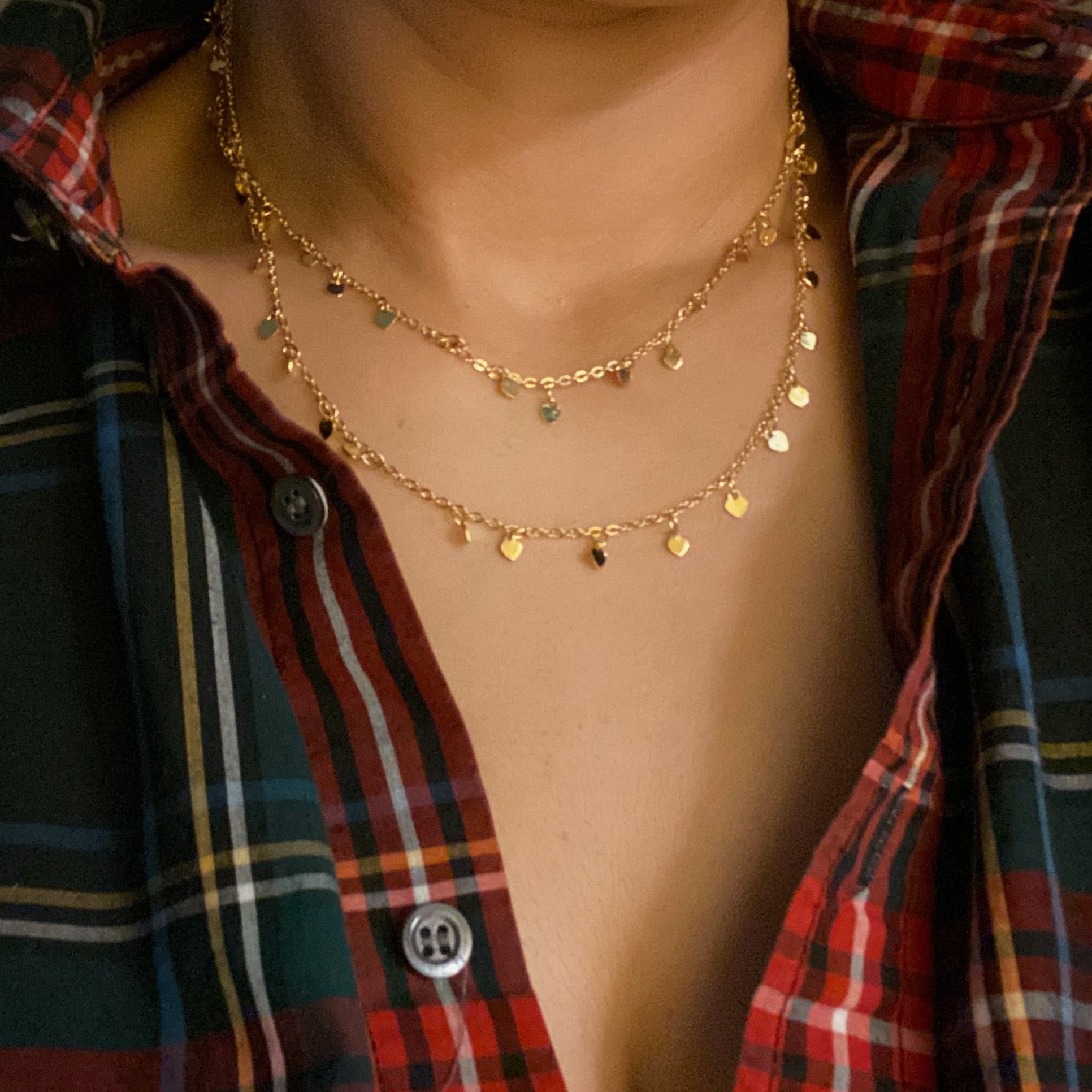 A long necklace featuring mini hearts on a gold chain, showcasing its elegant design and versatility.