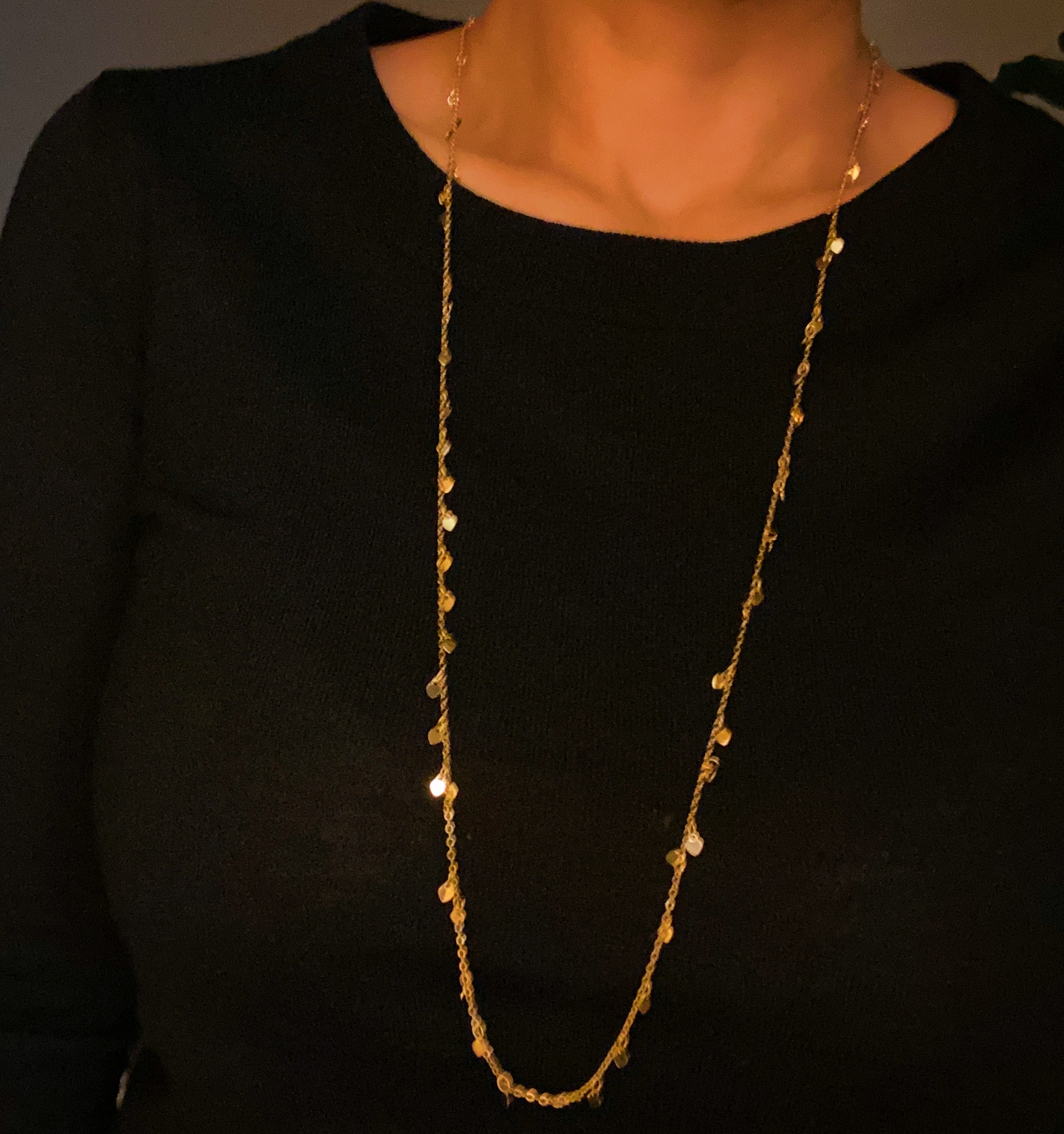 A long necklace featuring mini hearts on a gold chain, showcasing its elegant design and versatility.