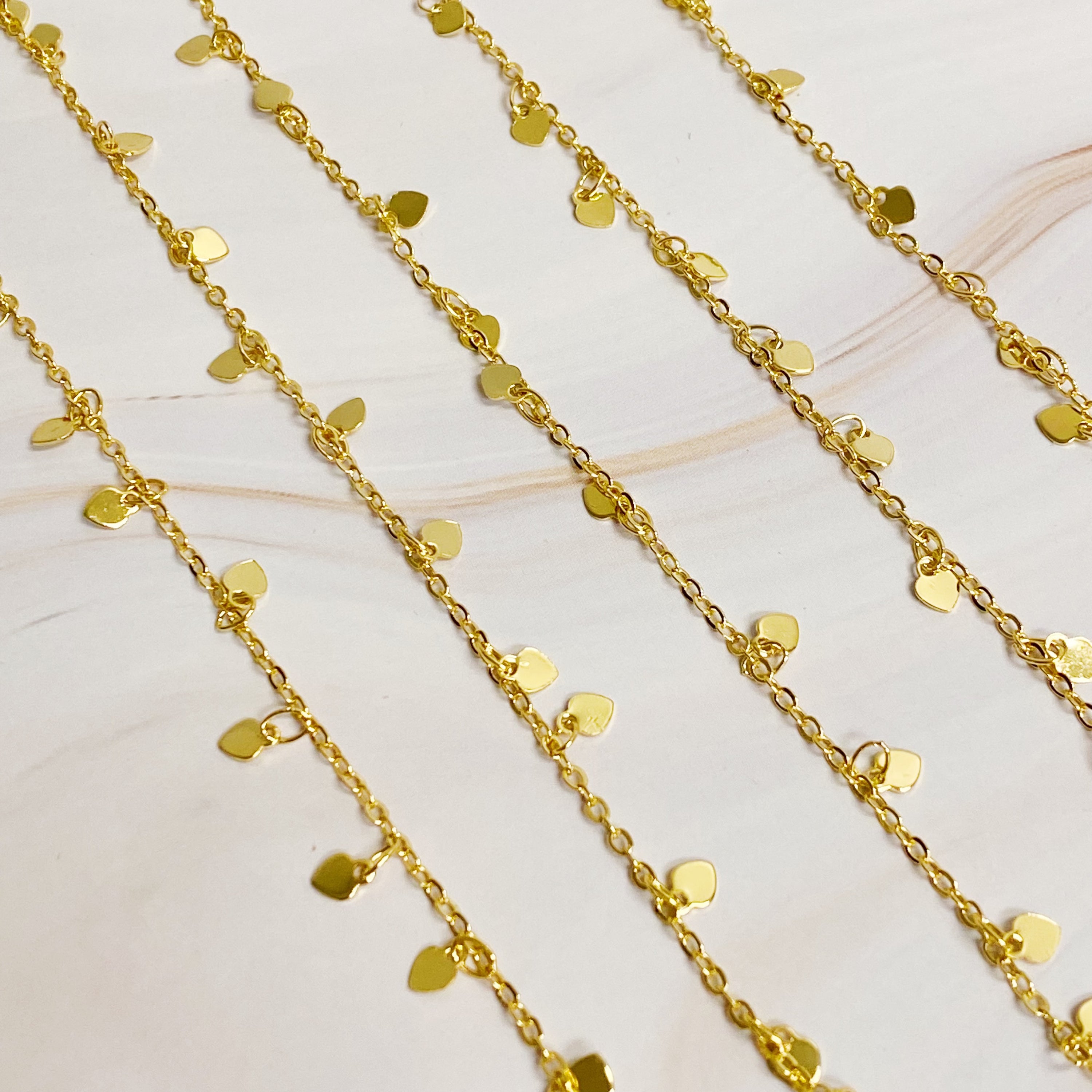 A long necklace featuring mini hearts on a gold chain, showcasing its elegant design and versatility.