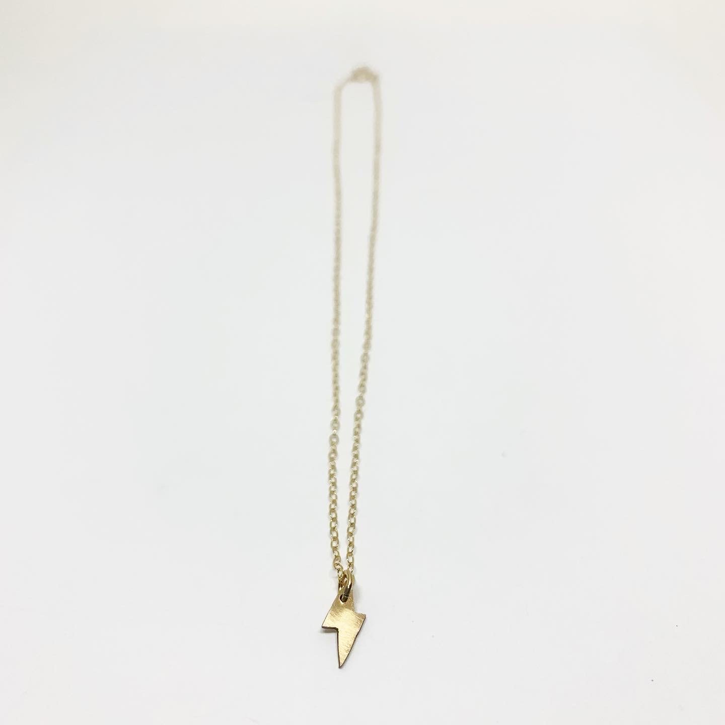 A delicate Mini Lightning Bolt Necklace made of sterling silver, showcasing a whimsical lightning bolt design, perfect for nature lovers.