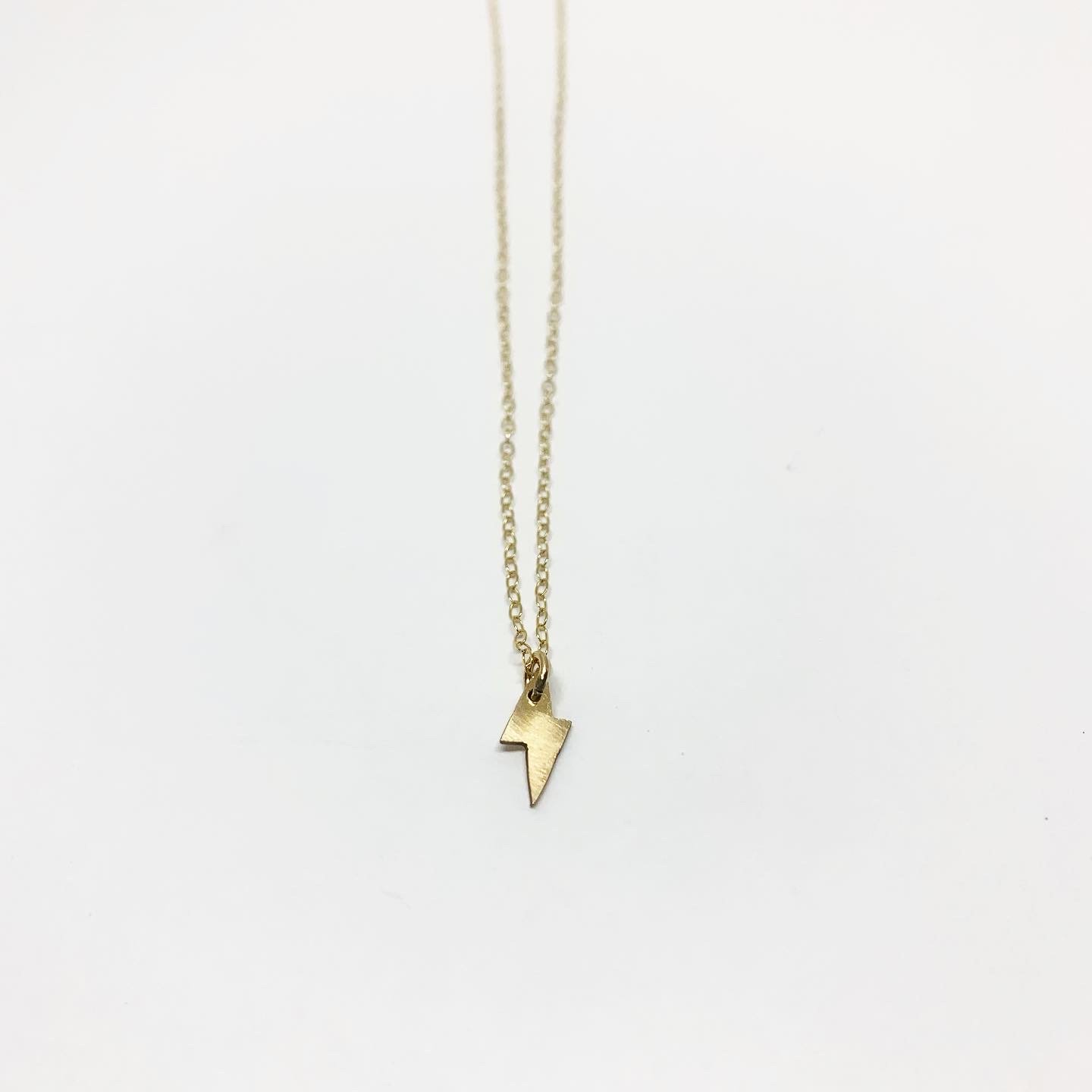 A delicate Mini Lightning Bolt Necklace made of sterling silver, showcasing a whimsical lightning bolt design, perfect for nature lovers.