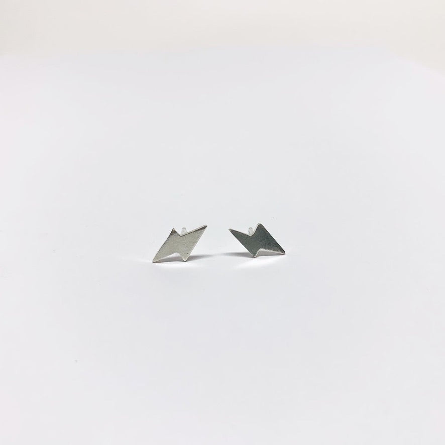 A pair of handmade mini lightning bolt stud earrings made from recycled sterling silver, showcasing a whimsical design.