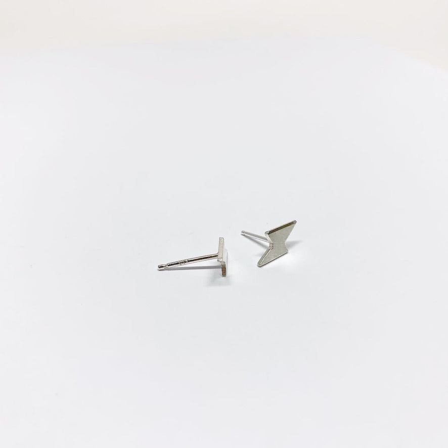 A pair of handmade mini lightning bolt stud earrings made from recycled sterling silver, showcasing a whimsical design.