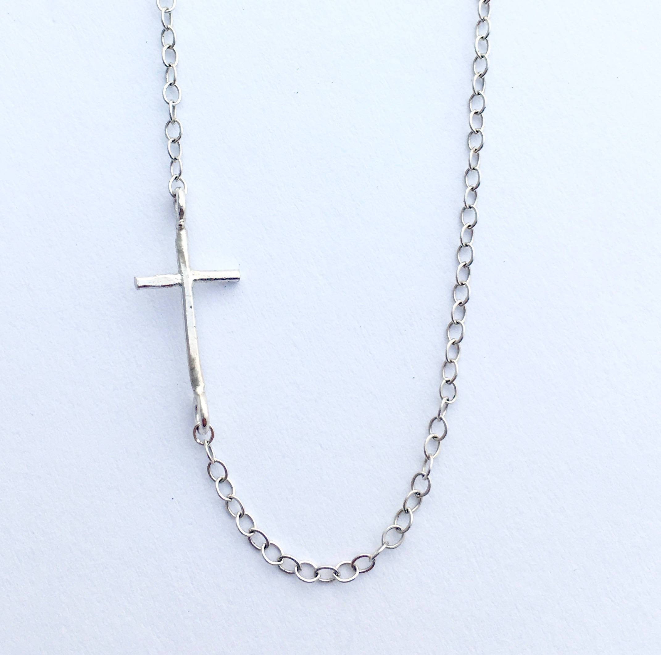 A delicate Mini Sideways Cross Necklace in sterling silver, featuring a handmade cross pendant on an adjustable chain.