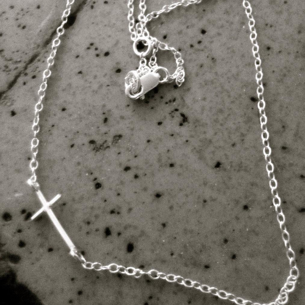 A delicate Mini Sideways Cross Necklace in sterling silver, featuring a handmade cross pendant on an adjustable chain.