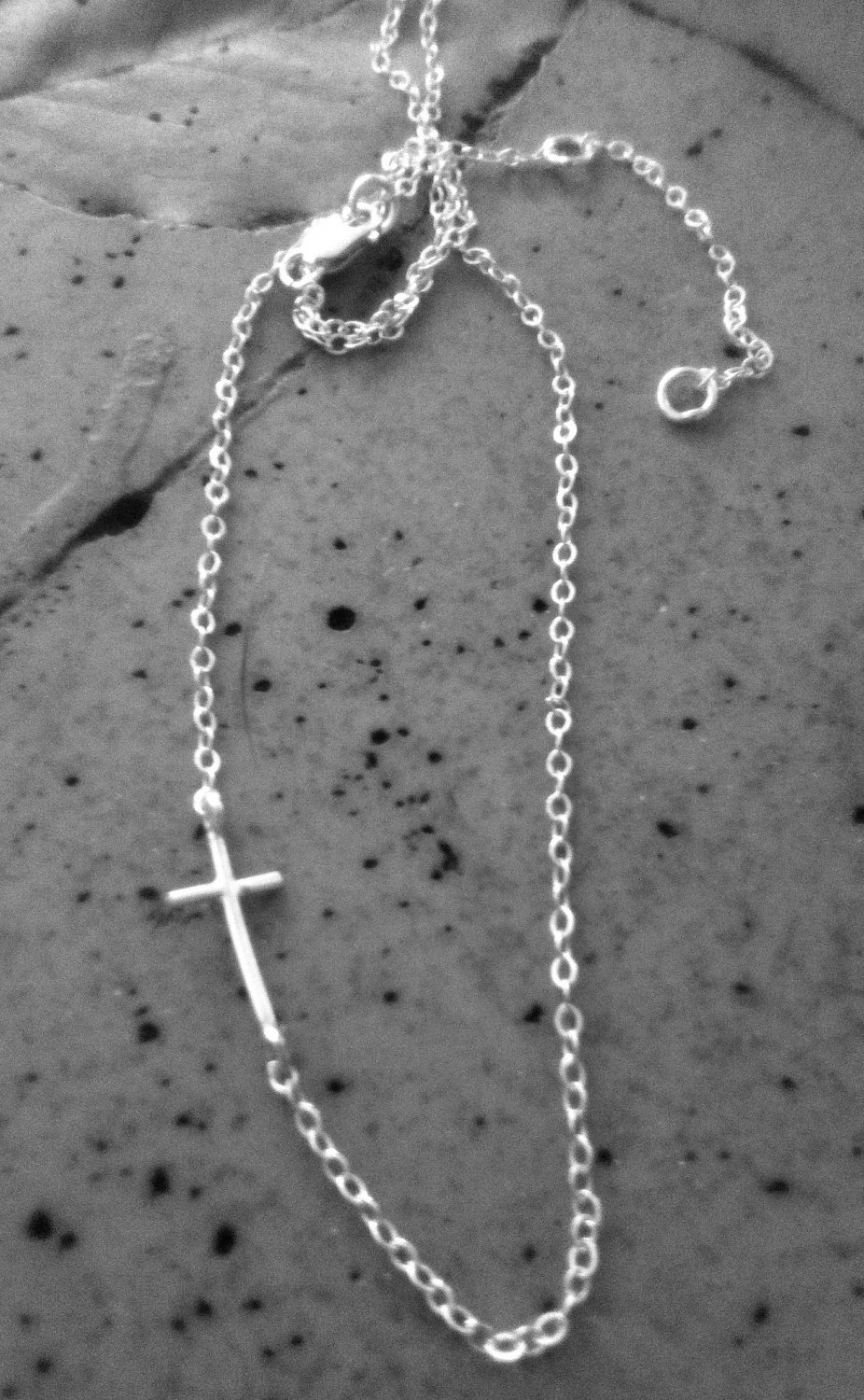 A delicate Mini Sideways Cross Necklace in sterling silver, featuring a handmade cross pendant on an adjustable chain.