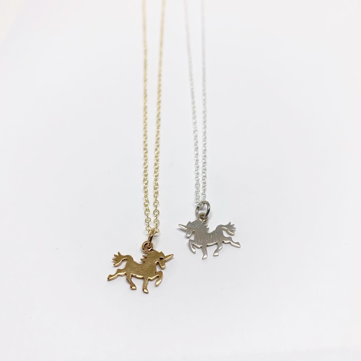 A delicate mini unicorn charm necklace featuring a sterling silver or brass pendant on a yellow gold fill chain, perfect for horse lovers.