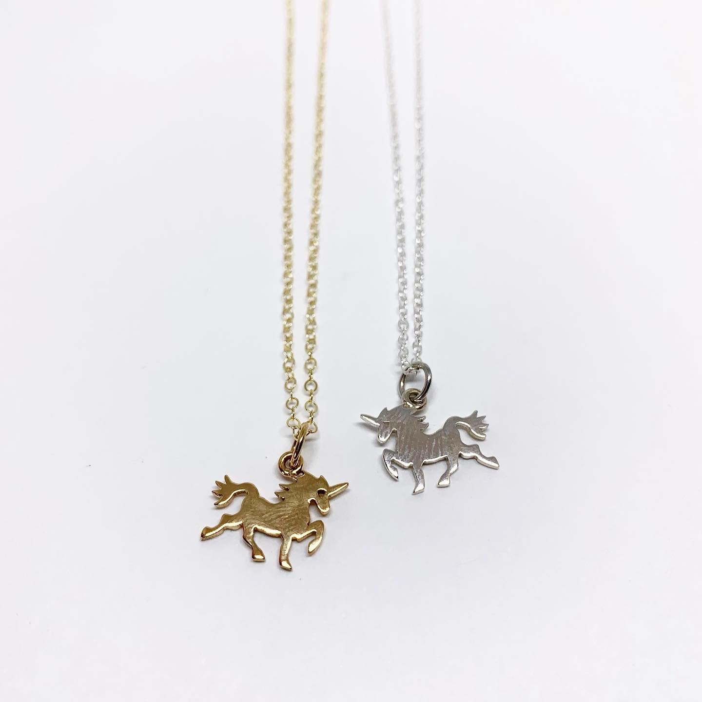 A delicate mini unicorn charm necklace featuring a sterling silver or brass pendant on a yellow gold fill chain, perfect for horse lovers.