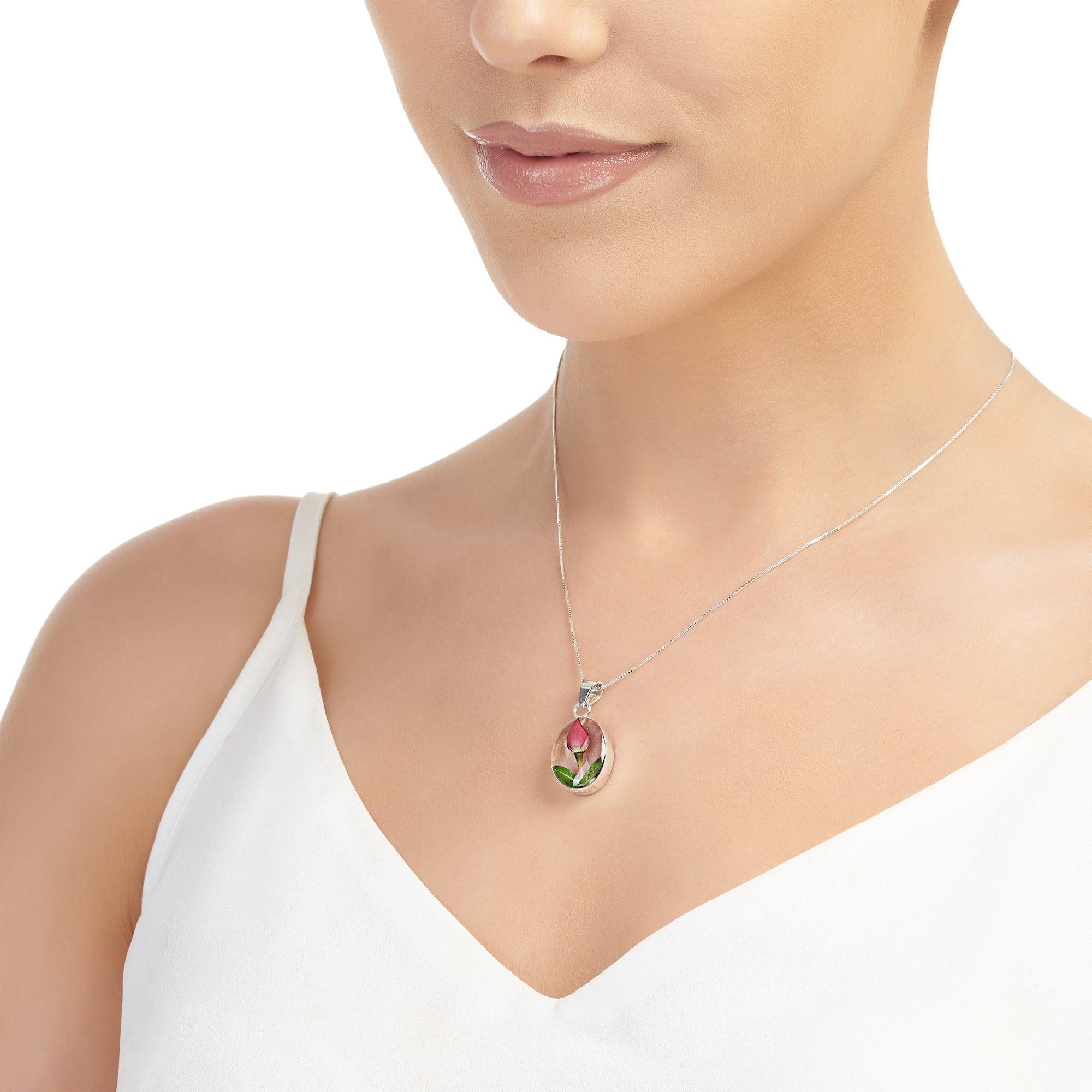 Miniature rose necklace featuring a sterling silver oval pendant with an adjustable chain, elegantly displayed in a gift box.