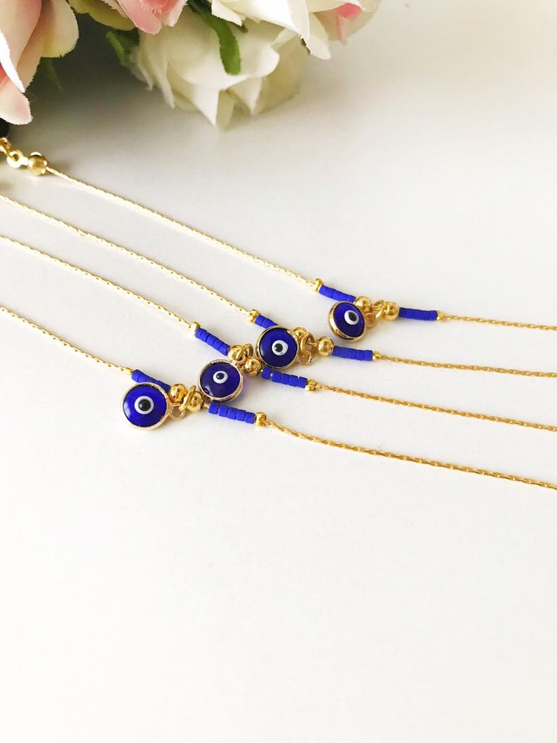 Minimal Evil Eye Bracelet featuring a blue glass charm and gold chain with tiny blue miyuki beads, elegantly designed for protection and style.