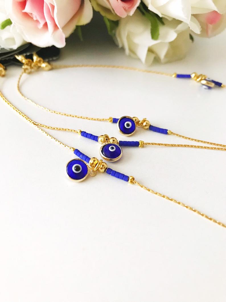 Minimal Evil Eye Bracelet featuring a blue glass charm and gold chain with tiny blue miyuki beads, elegantly designed for protection and style.