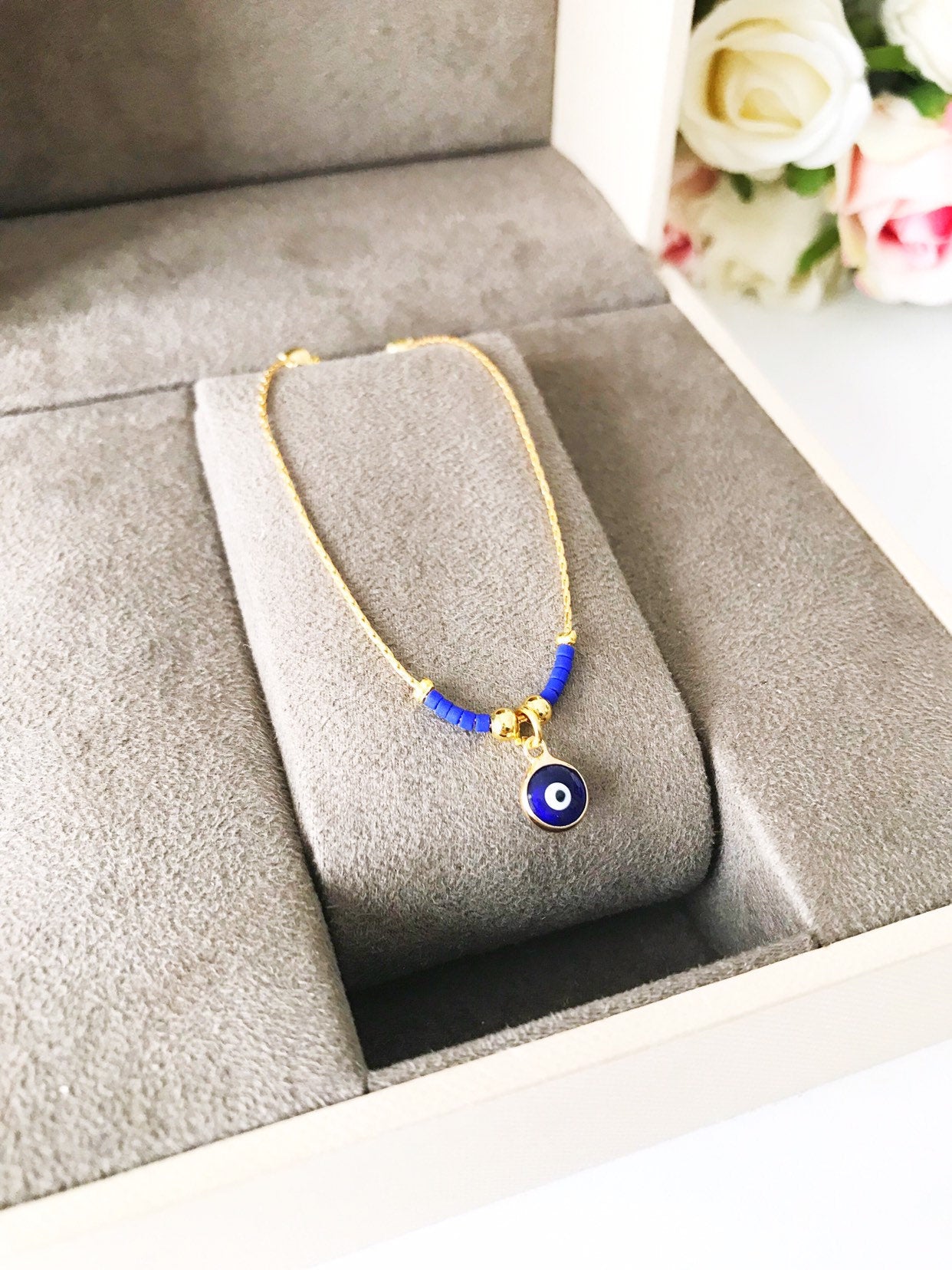 Minimal Evil Eye Bracelet featuring a blue glass charm and gold chain with tiny blue miyuki beads, elegantly designed for protection and style.