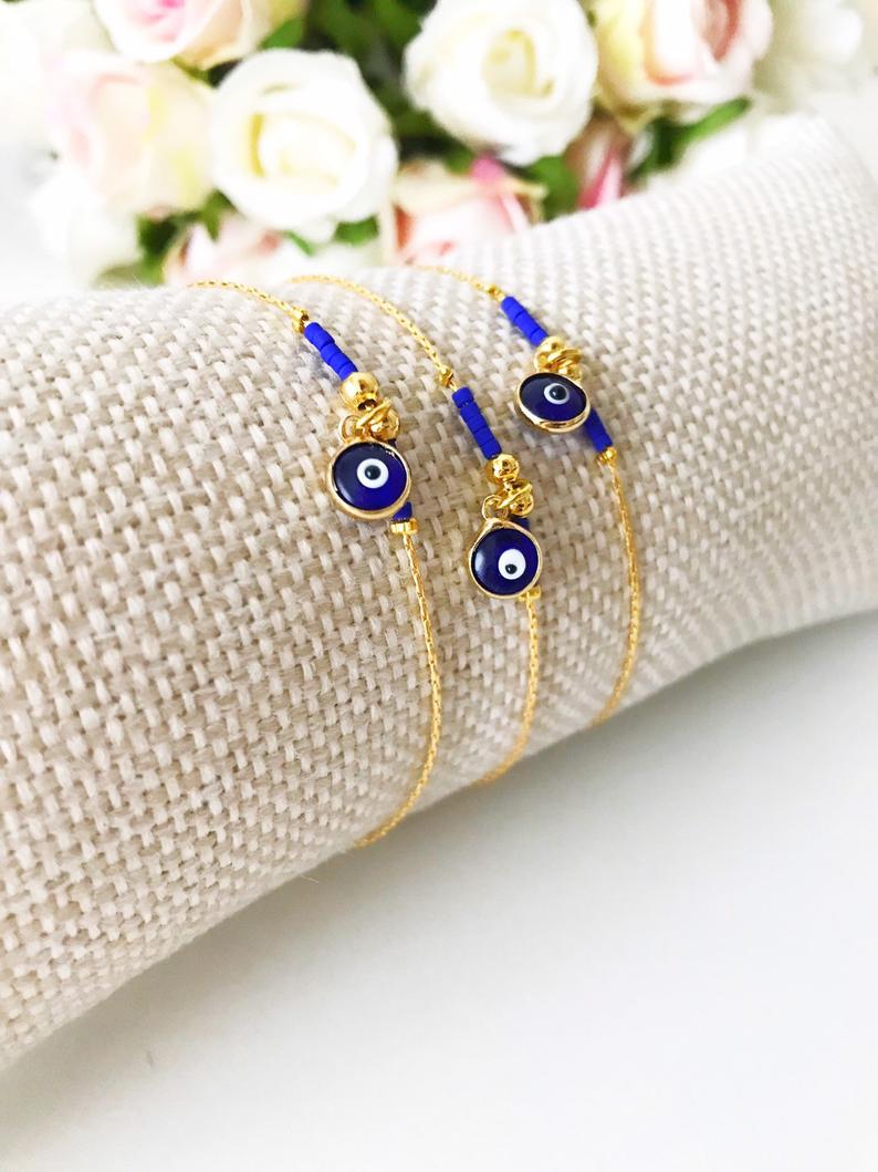 Minimal Evil Eye Bracelet featuring a blue glass charm and gold chain with tiny blue miyuki beads, elegantly designed for protection and style.