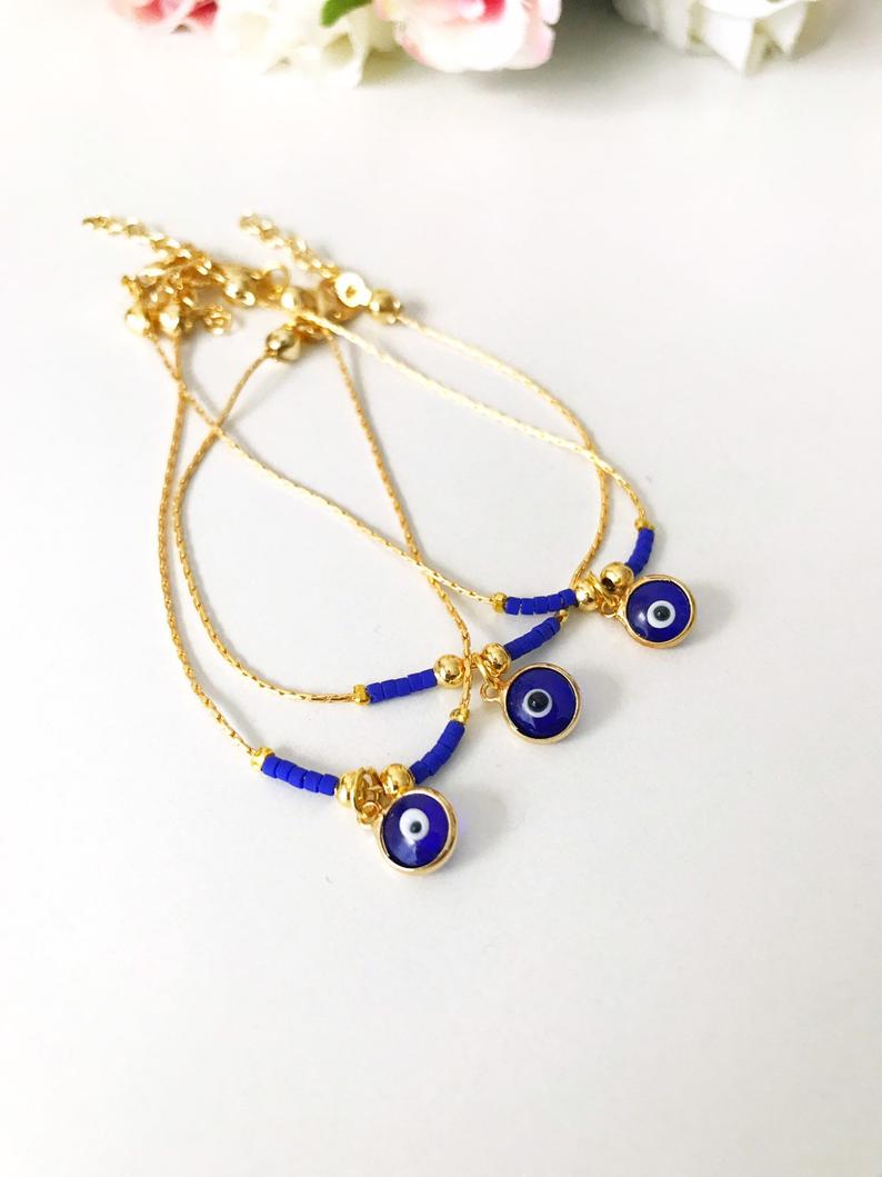 Minimal Evil Eye Bracelet featuring a blue glass charm and gold chain with tiny blue miyuki beads, elegantly designed for protection and style.