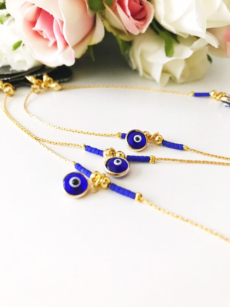 Minimal Evil Eye Bracelet featuring a blue glass charm and gold chain with tiny blue miyuki beads, elegantly designed for protection and style.