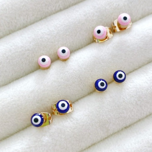 A pair of elegant gold minimal stud earrings featuring a tiny evil eye design in pink and blue options.