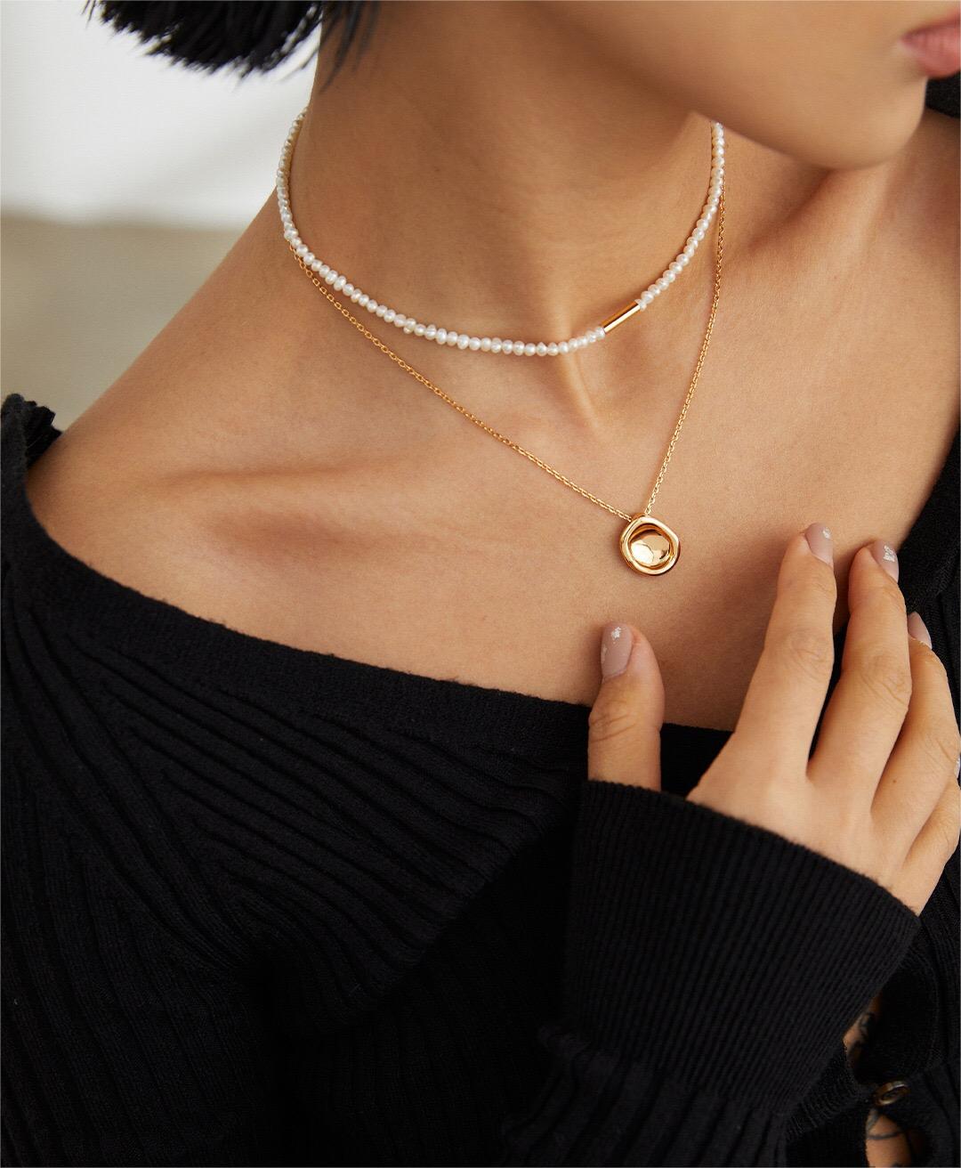 A close-up of the Minimalist Abstract Stacking Pebble Necklace showcasing its gold vermeil finish and unique pebble pendant design.