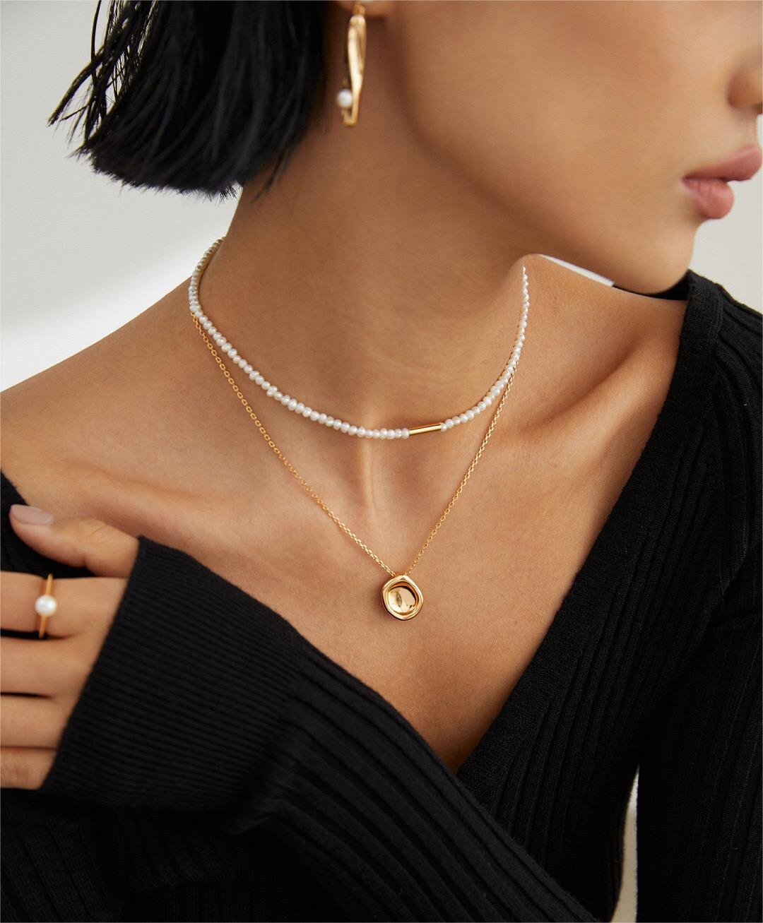 A close-up of the Minimalist Abstract Stacking Pebble Necklace showcasing its gold vermeil finish and unique pebble pendant design.