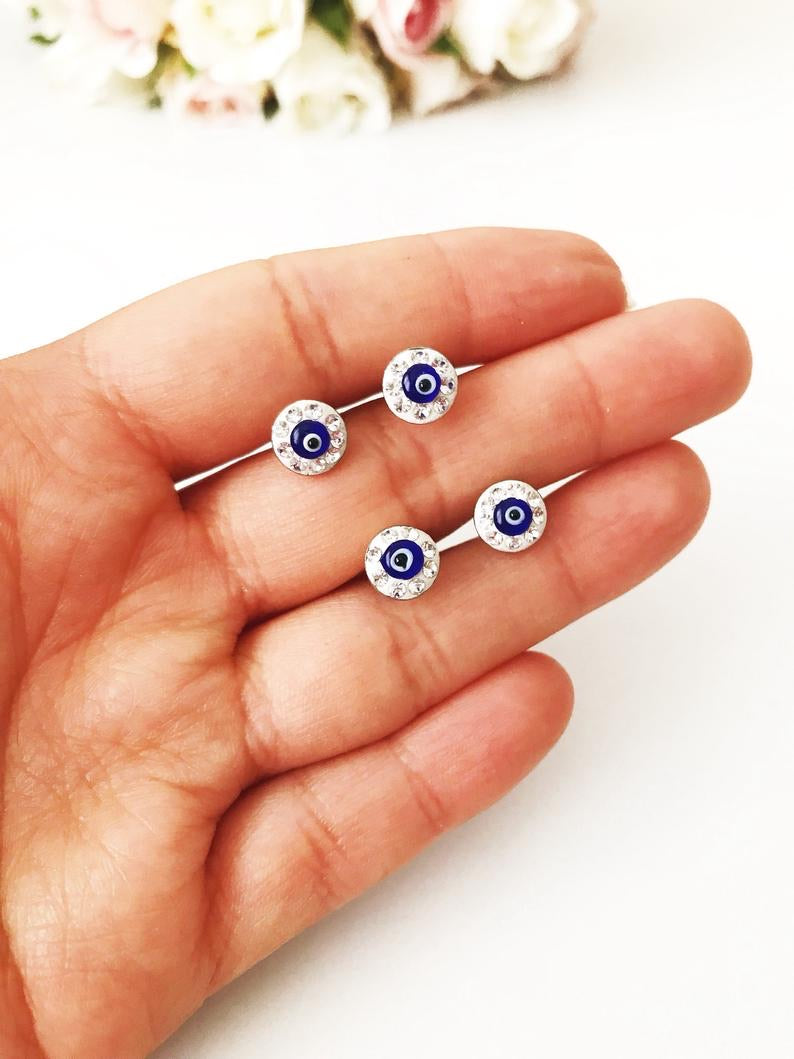 A pair of handmade minimalist earrings featuring blue evil eye beads set in silver, symbolizing protection and style.