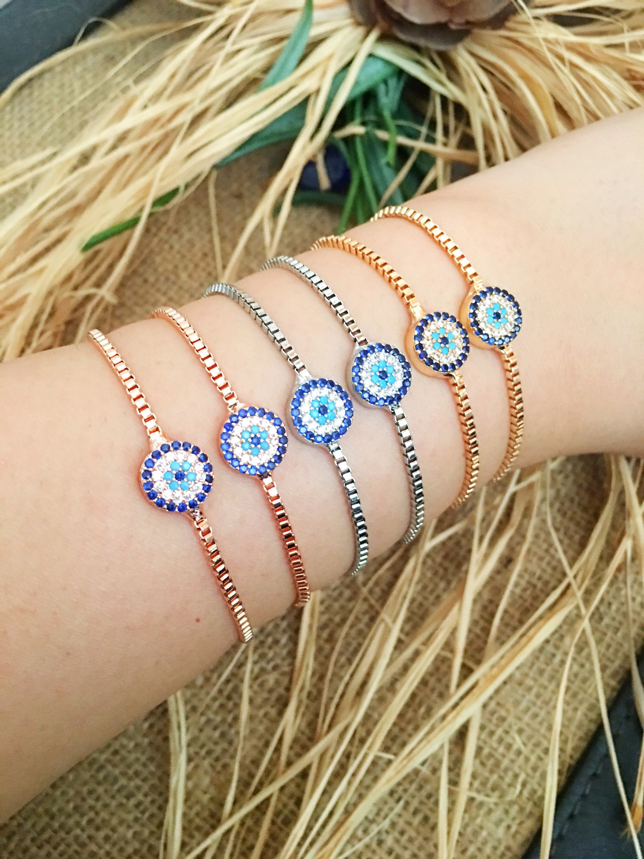 A stylish Minimalist Evil Eye Bracelet featuring an adjustable design in rose gold, silver, and gold with a sparkling evil eye charm.