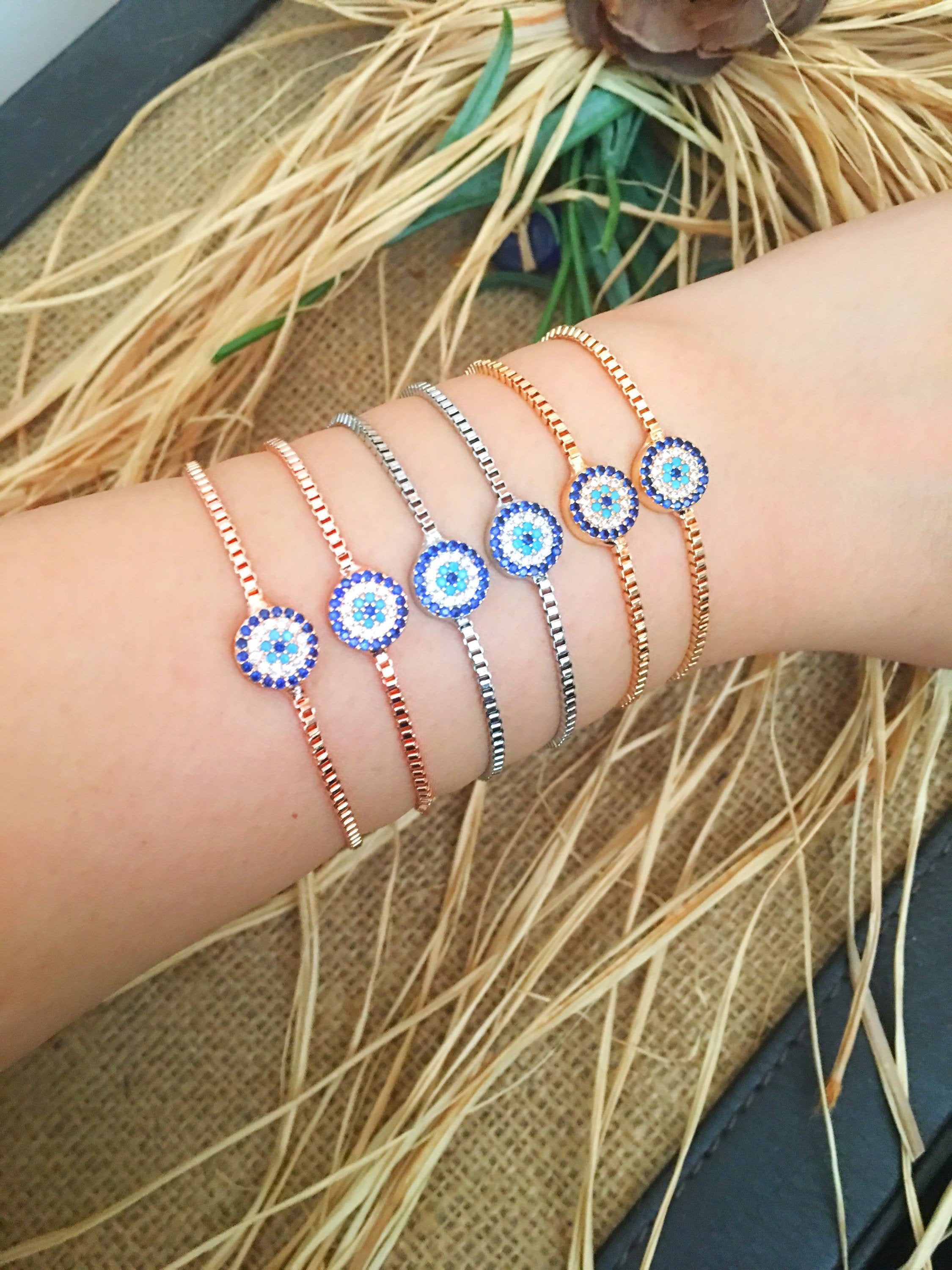 A stylish Minimalist Evil Eye Bracelet featuring an adjustable design in rose gold, silver, and gold with a sparkling evil eye charm.