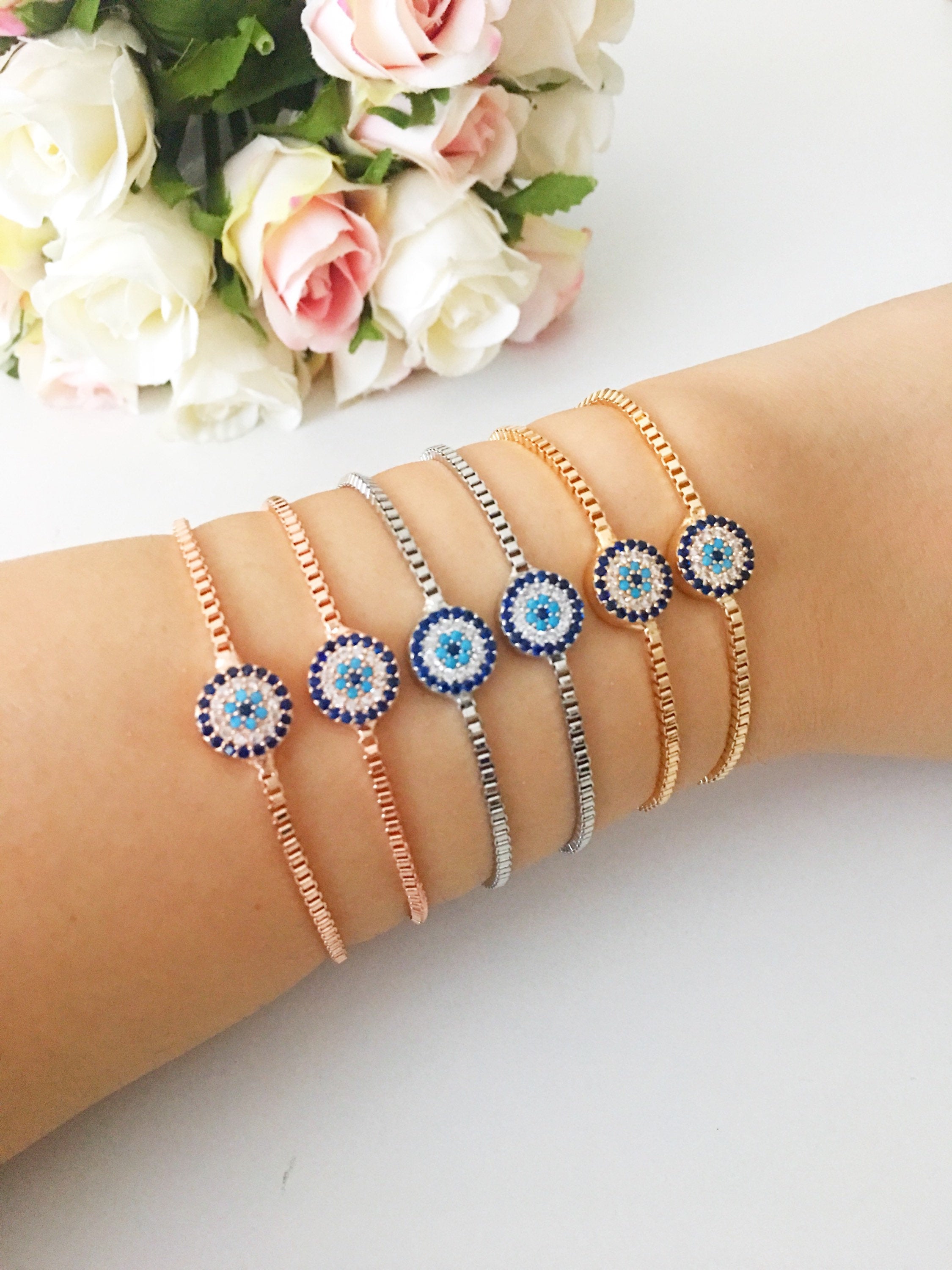 A stylish Minimalist Evil Eye Bracelet featuring an adjustable design in rose gold, silver, and gold with a sparkling evil eye charm.