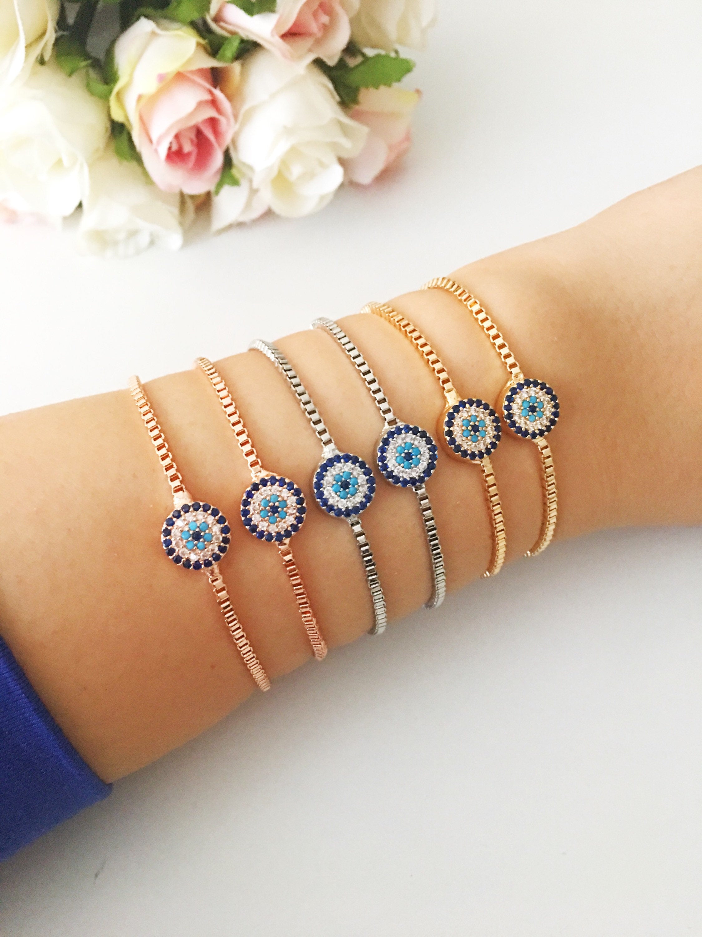 A stylish Minimalist Evil Eye Bracelet featuring an adjustable design in rose gold, silver, and gold with a sparkling evil eye charm.