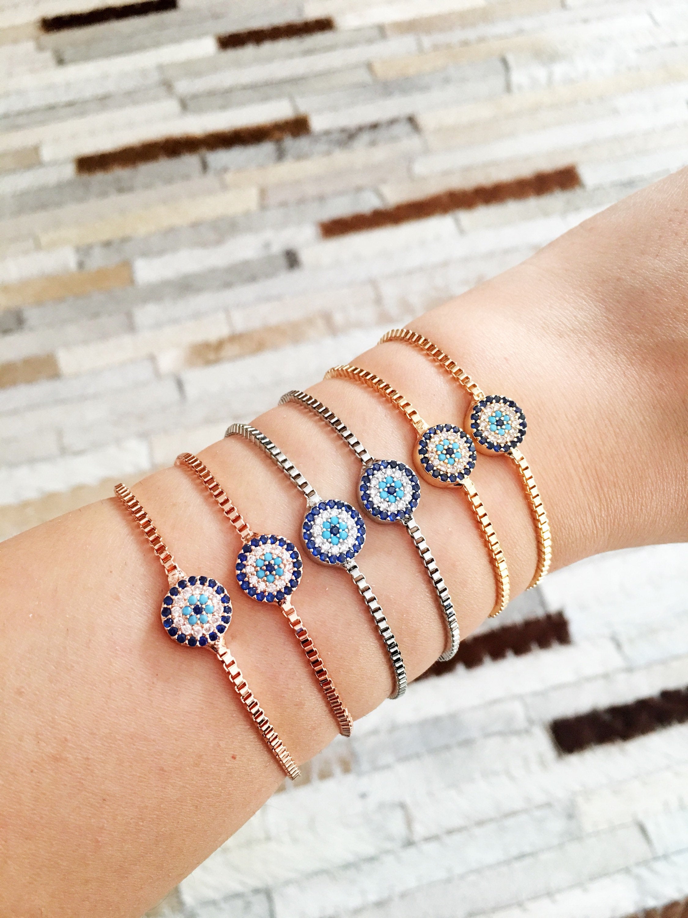 A stylish Minimalist Evil Eye Bracelet featuring an adjustable design in rose gold, silver, and gold with a sparkling evil eye charm.