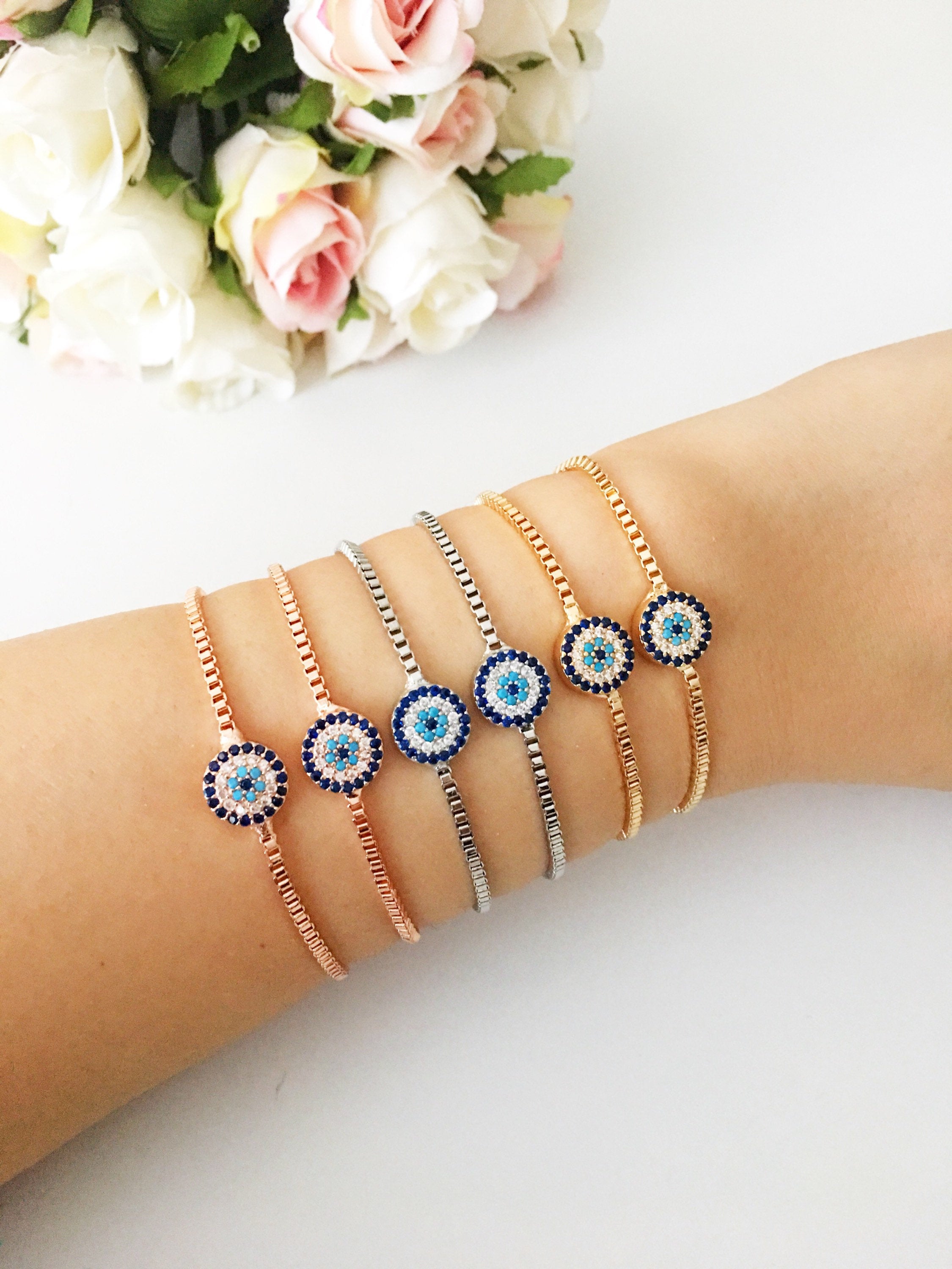 A stylish Minimalist Evil Eye Bracelet featuring an adjustable design in rose gold, silver, and gold with a sparkling evil eye charm.