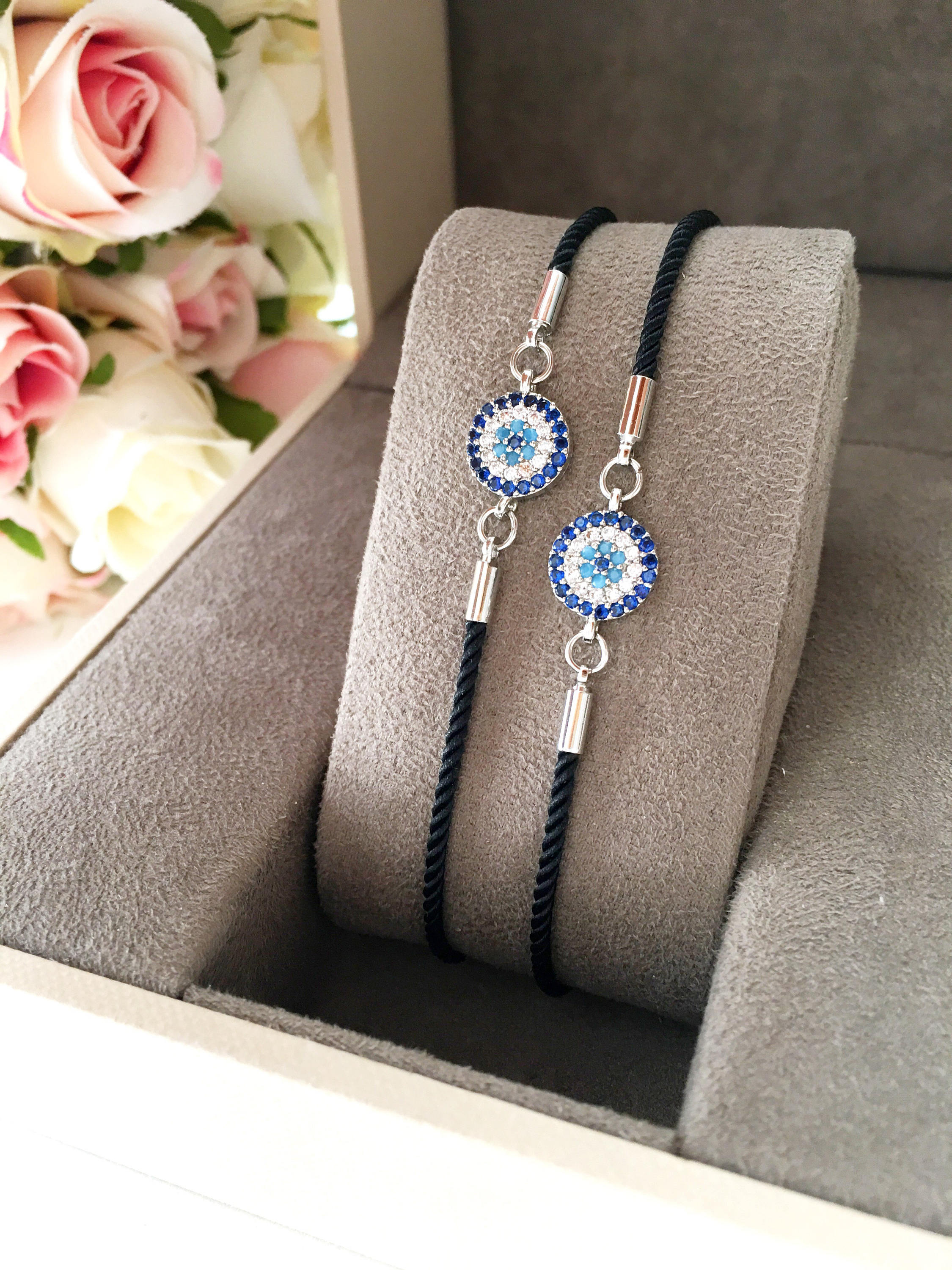 Minimalist Evil Eye Bracelet featuring an adjustable black string and a silver evil eye charm, showcasing its elegant design and craftsmanship.