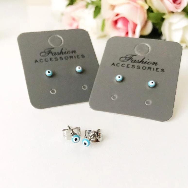 A pair of handmade minimalist evil eye stud earrings with a silver finish, featuring a blue evil eye design, symbolizing protection and good luck.