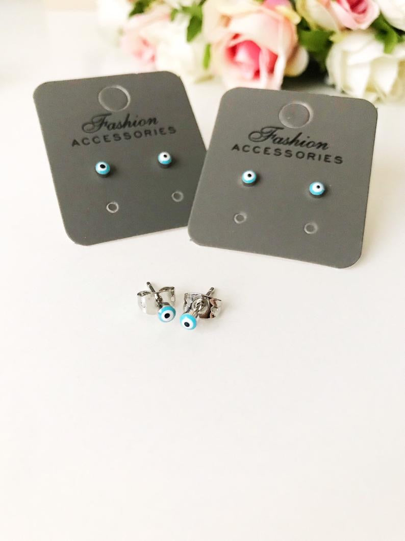 A pair of handmade minimalist evil eye stud earrings with a silver finish, featuring a blue evil eye design, symbolizing protection and good luck.