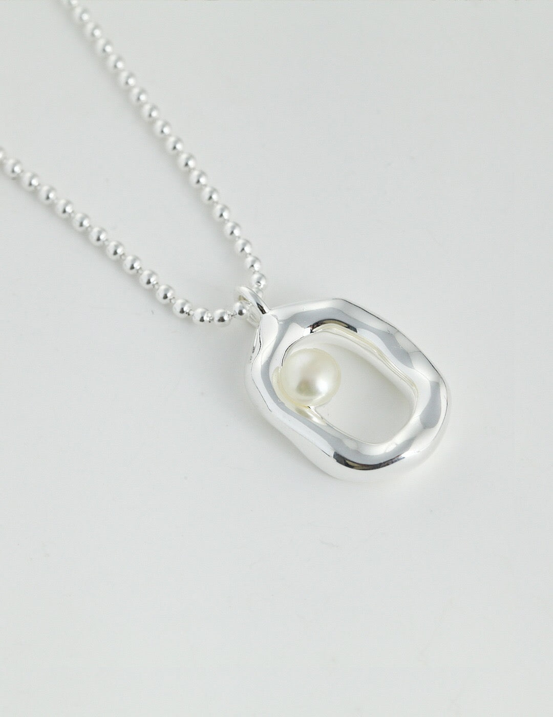 A beautiful Minimalist O-shaped Pearl Pendant Necklace featuring a natural pearl and gold vermeil, elegantly displayed on a soft background.