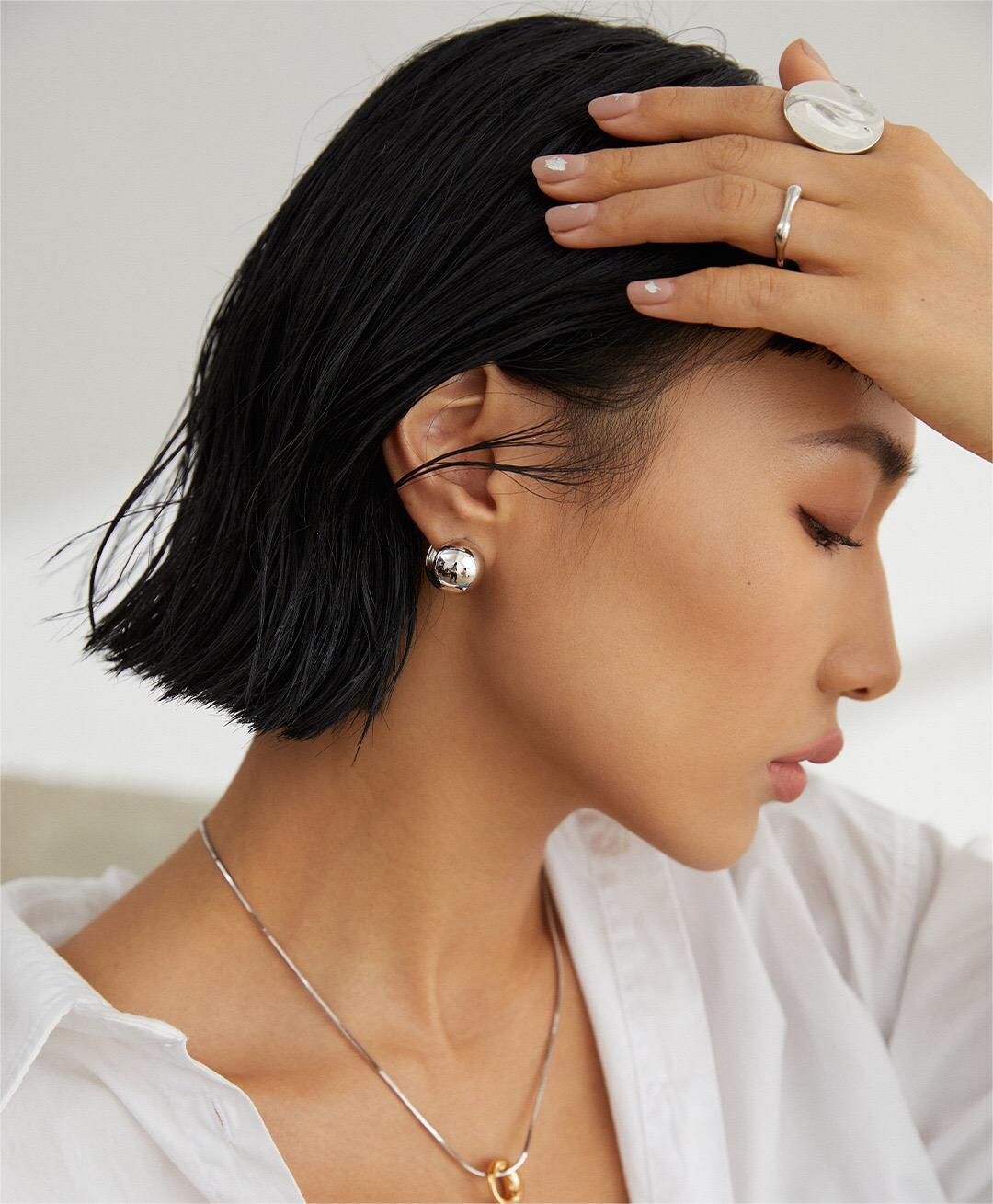 A pair of elegant Minimalist Round Ball Earrings made from sterling silver and gold vermeil, showcasing their shiny, round design.