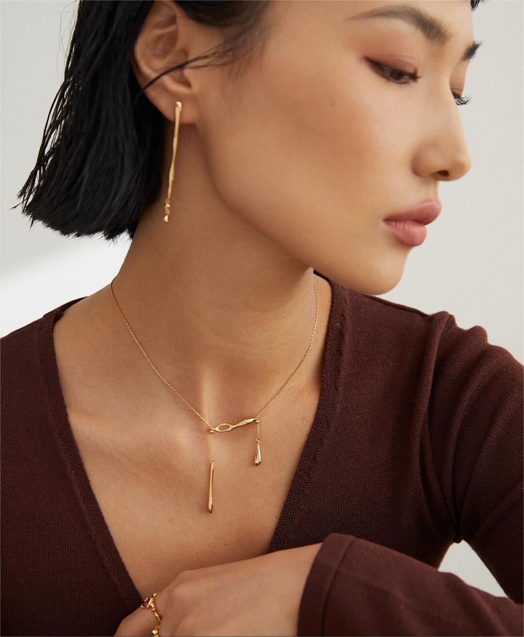 A delicate Minimalist Water Droplets Style Necklace made of sterling silver with a gold vermeil finish, showcasing a unique water droplet design.