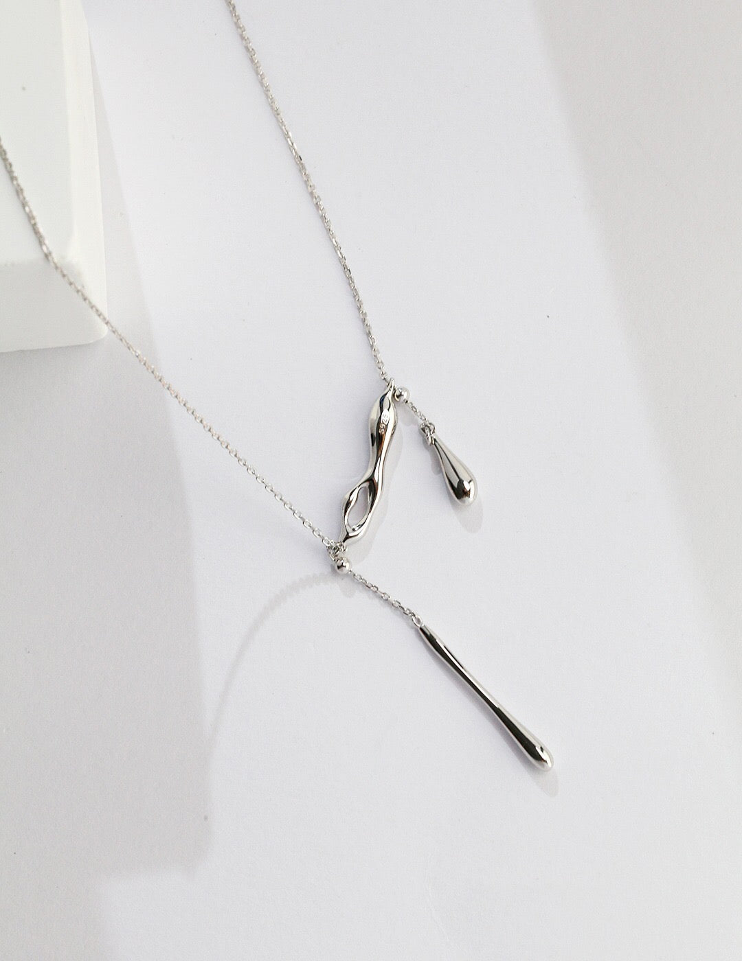 A delicate Minimalist Water Droplets Style Necklace made of sterling silver with a gold vermeil finish, showcasing a unique water droplet design.