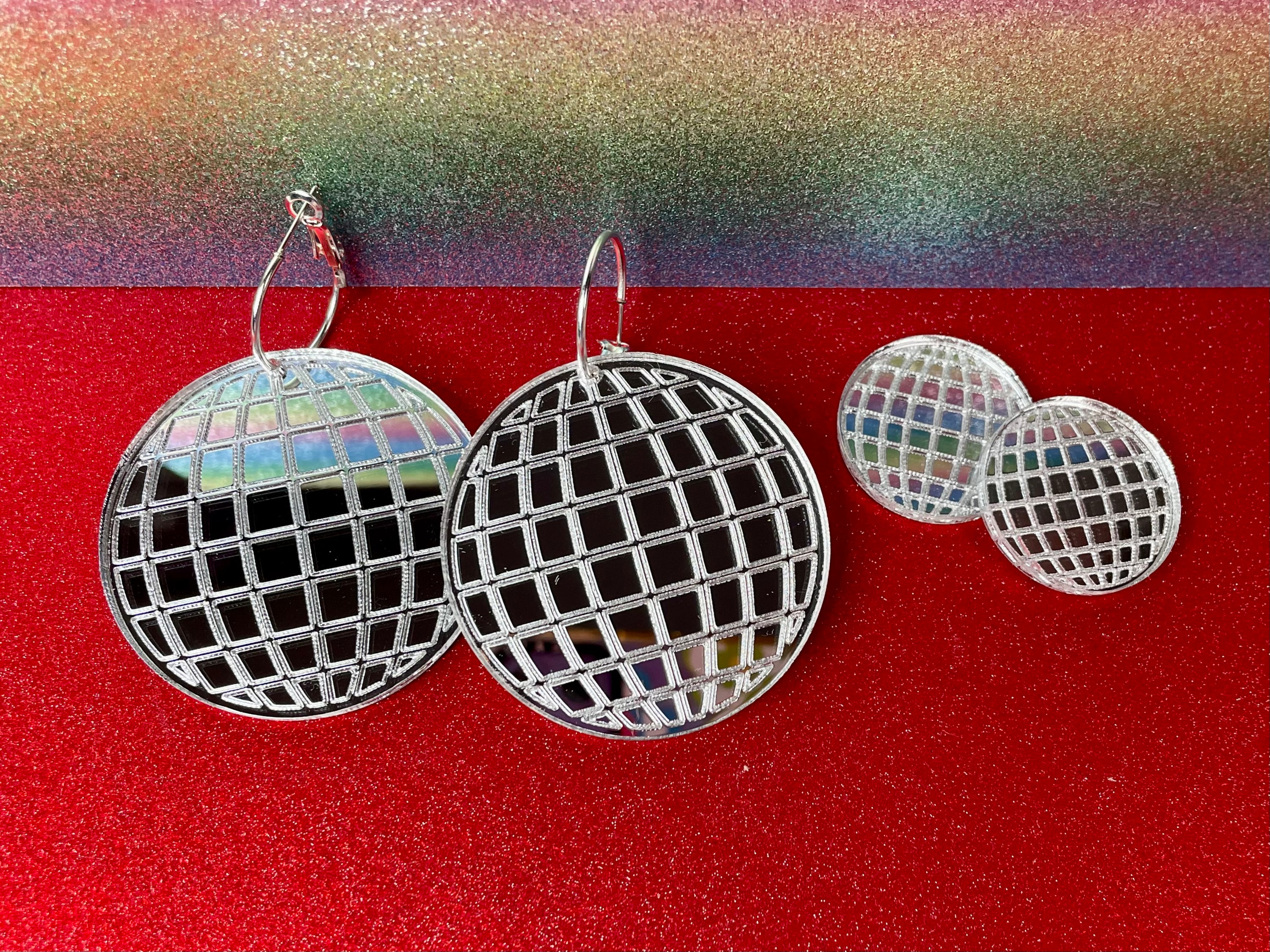 A pair of dazzling Mirror Ball Earrings featuring colorful mirror finishes, available as dangles or studs, showcasing their unique design.