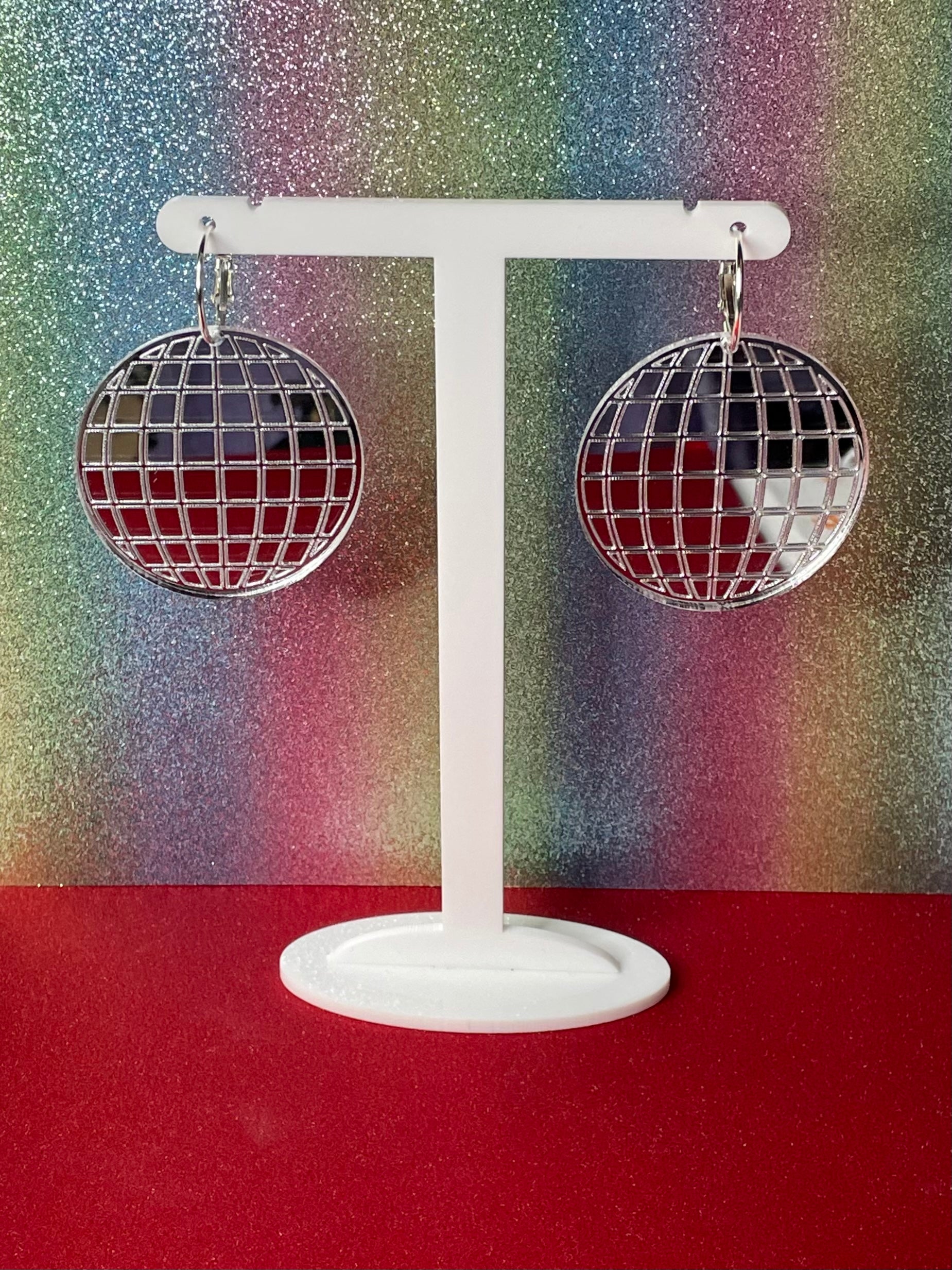 A pair of dazzling Mirror Ball Earrings featuring colorful mirror finishes, available as dangles or studs, showcasing their unique design.