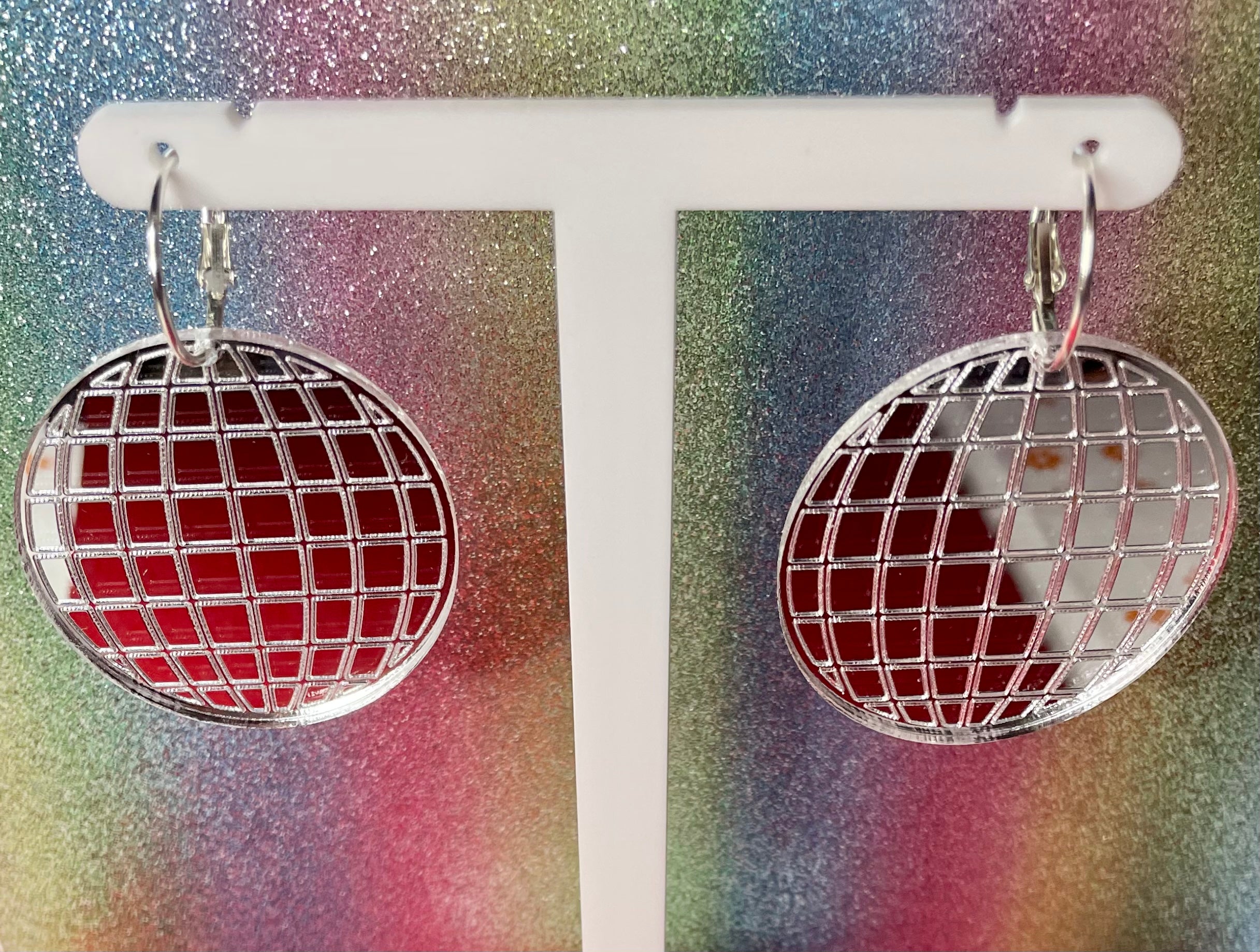 A pair of dazzling Mirror Ball Earrings featuring colorful mirror finishes, available as dangles or studs, showcasing their unique design.