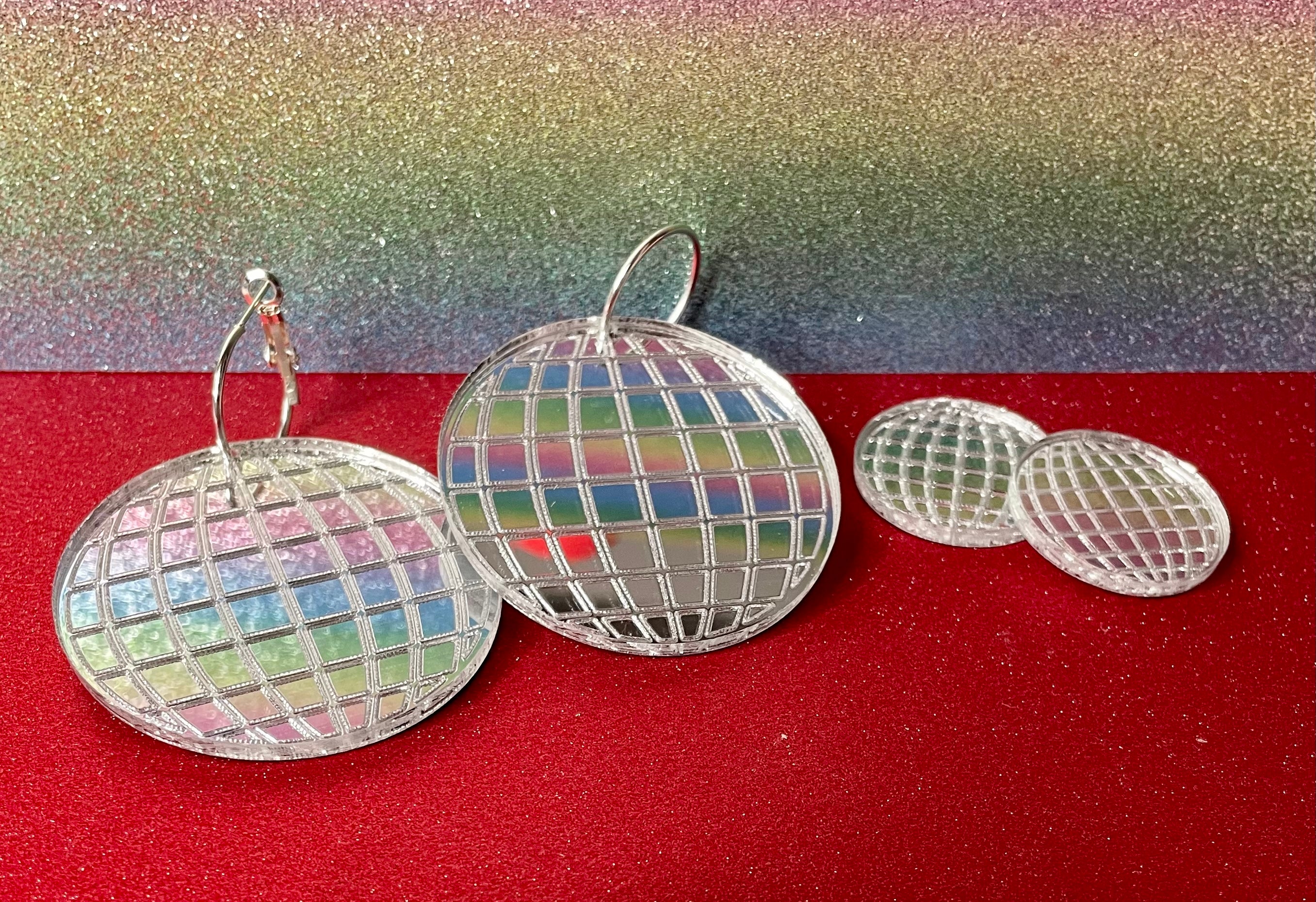 A pair of dazzling Mirror Ball Earrings featuring colorful mirror finishes, available as dangles or studs, showcasing their unique design.