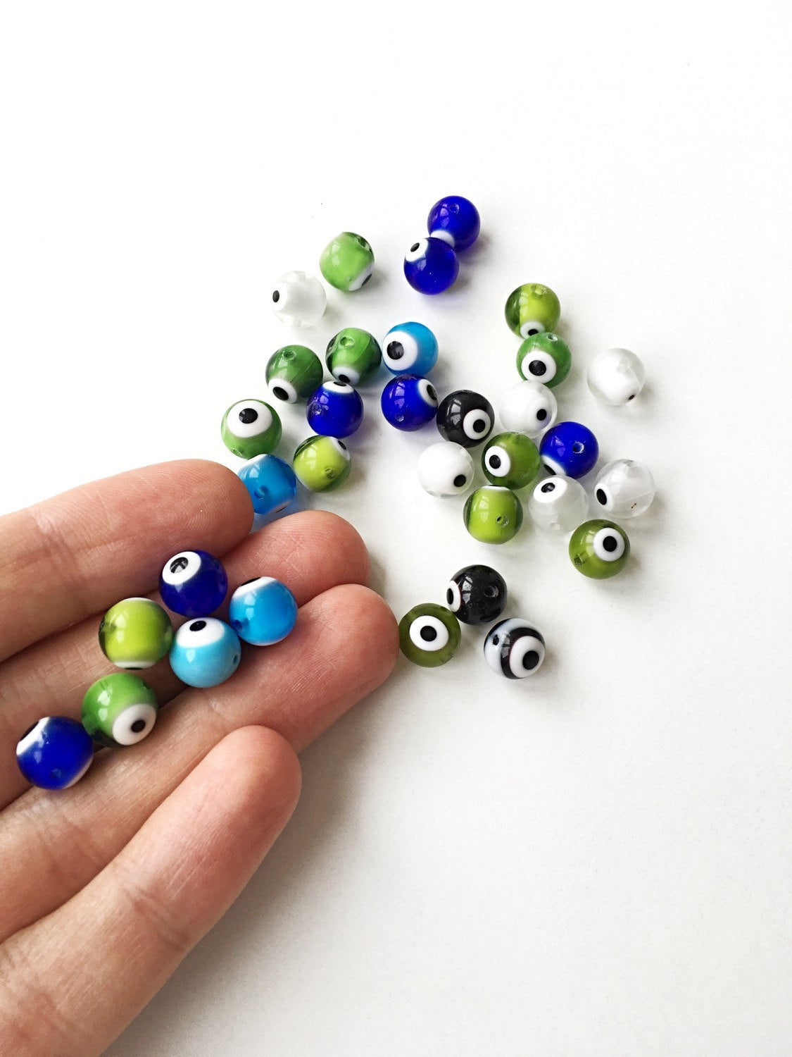 A collection of mixed color evil eye beads in 6mm, 8mm, and 10mm sizes, showcasing their vibrant designs and handmade quality.