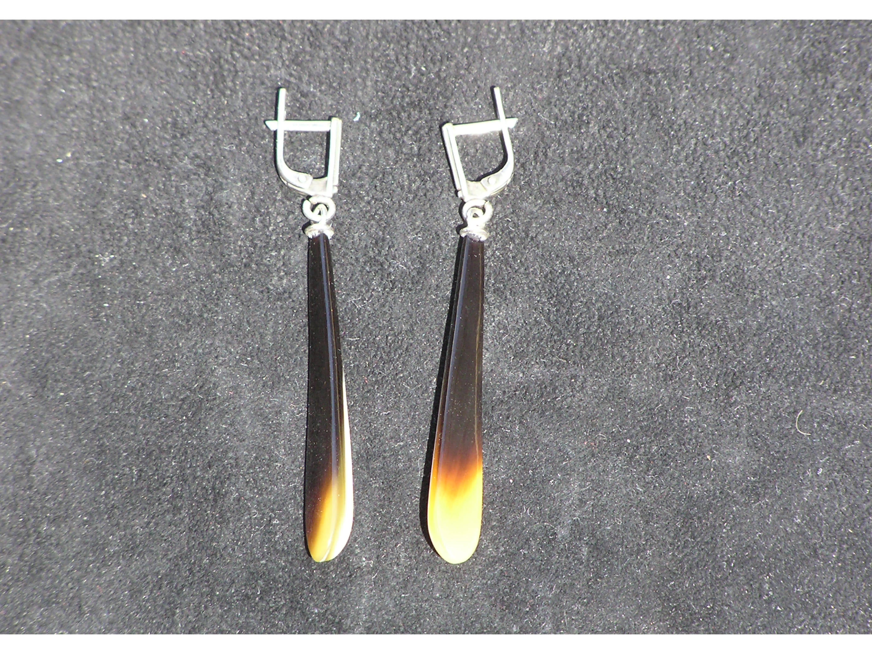 A pair of exclusive handmade modern statement earrings crafted from natural horn, featuring a luxurious design with a smooth surface and silver English locks.