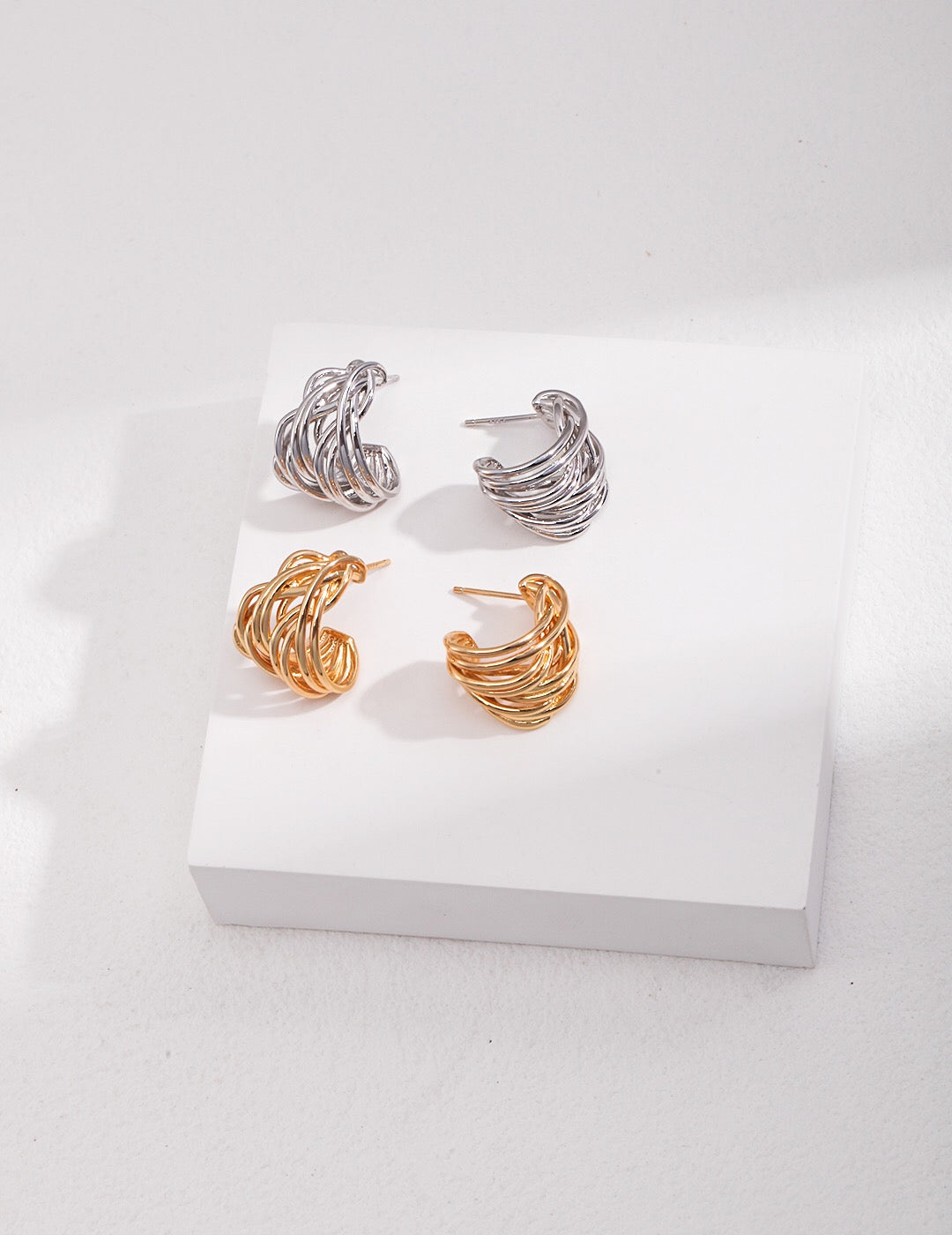 A pair of Modern Wave Hoop Earrings made from sterling silver and gold vermeil, showcasing a unique wave design.