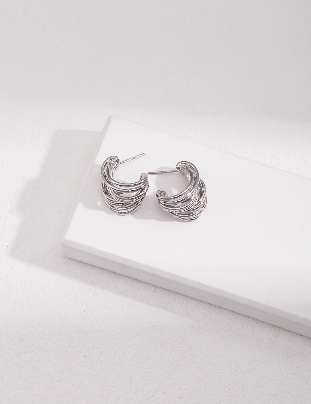 A pair of Modern Wave Hoop Earrings made from sterling silver and gold vermeil, showcasing a unique wave design.