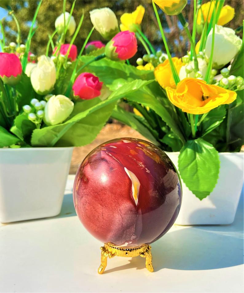 A beautifully crafted Mookaite Jasper Sphere showcasing vibrant colors of red, yellow, purple, and brown, symbolizing emotional growth and connection to nature.