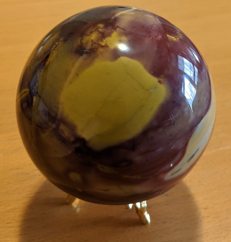 A beautifully crafted Mookaite Jasper Sphere showcasing vibrant colors of red, yellow, purple, and brown, symbolizing emotional growth and connection to nature.