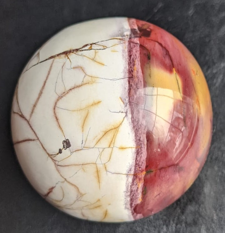 A beautifully crafted Mookaite Jasper Sphere showcasing vibrant colors of red, yellow, purple, and brown, symbolizing emotional growth and connection to nature.