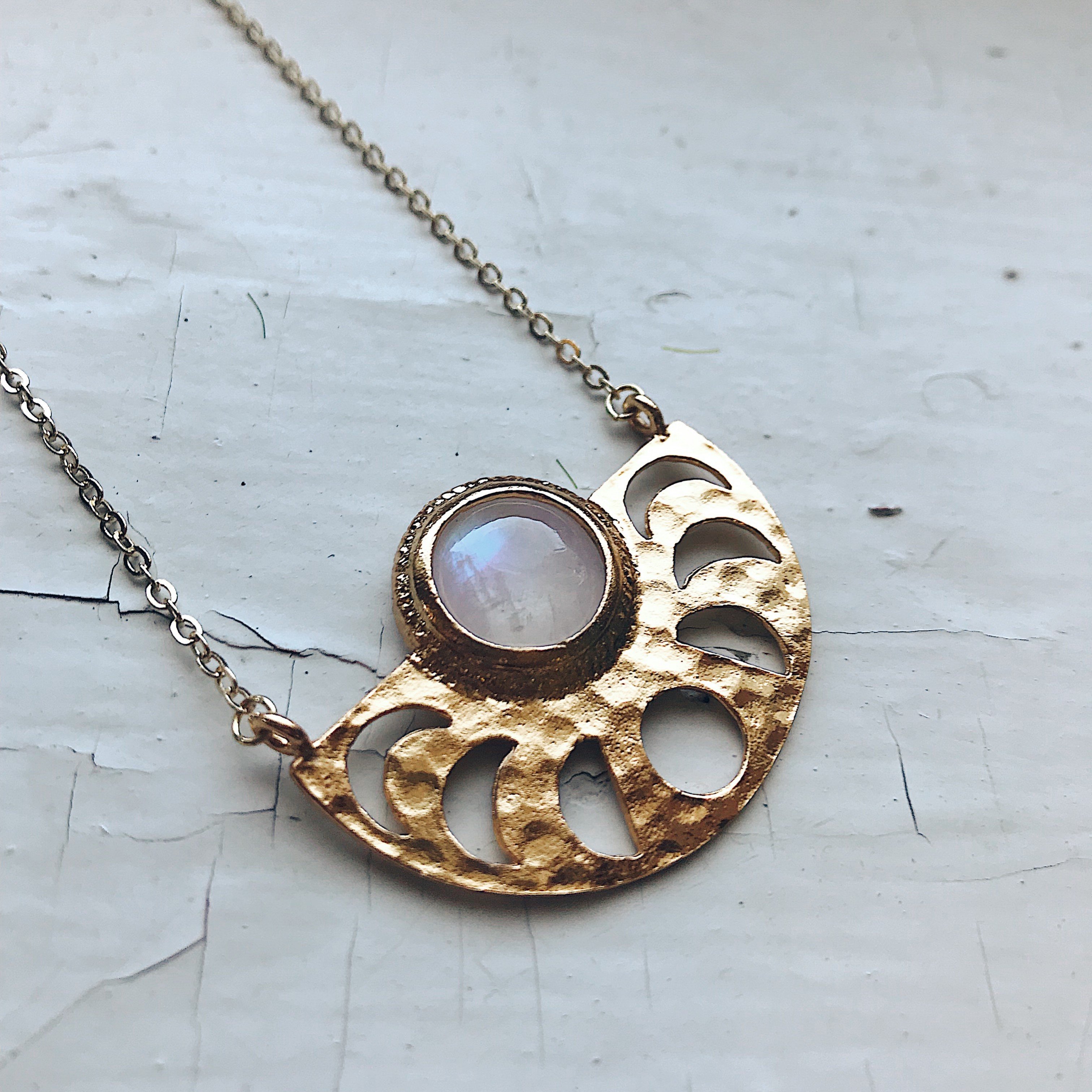 Moon Goddess Necklace featuring a gold tone raw brass pendant with phases of the Moon and a rainbow Moonstone centerpiece.