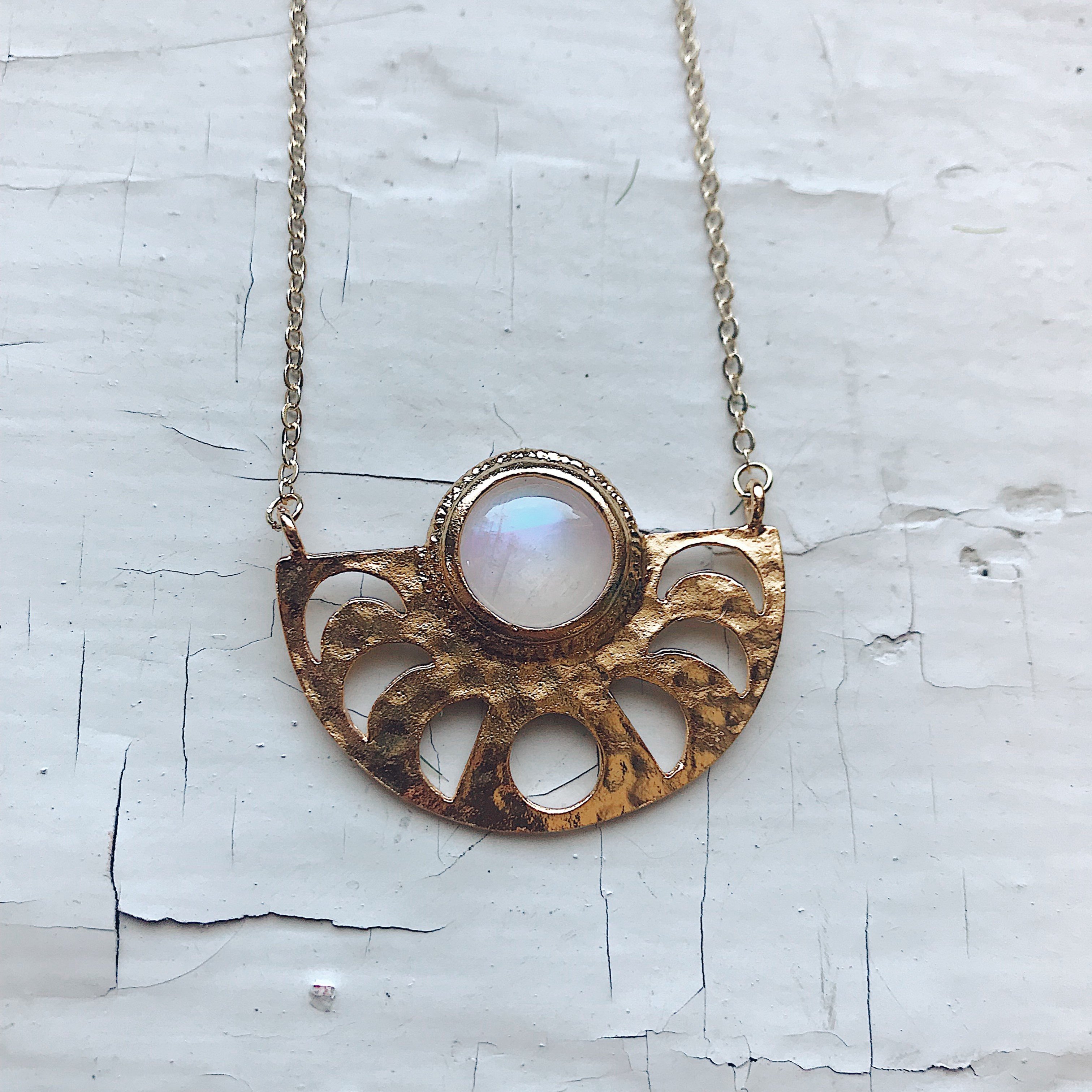 Moon Goddess Necklace featuring a gold tone raw brass pendant with phases of the Moon and a rainbow Moonstone centerpiece.