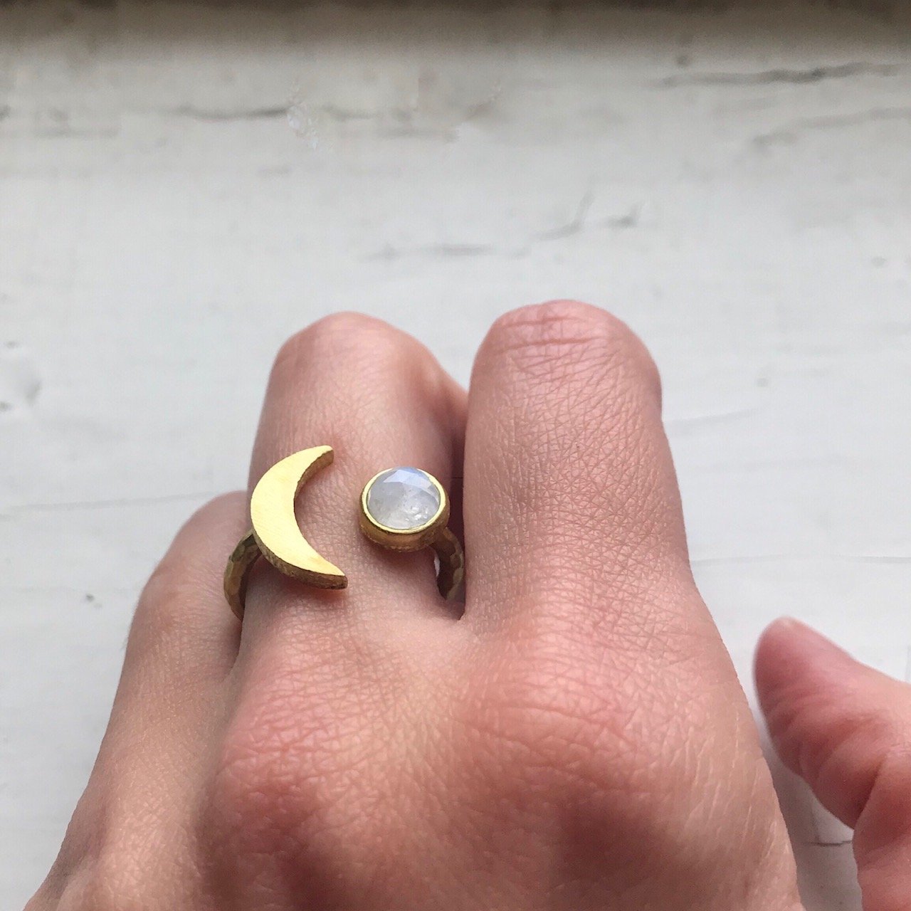 Moon Goddess Ring featuring a hammered crescent design and a 6mm rainbow Moonstone, available in gold and silver tones.